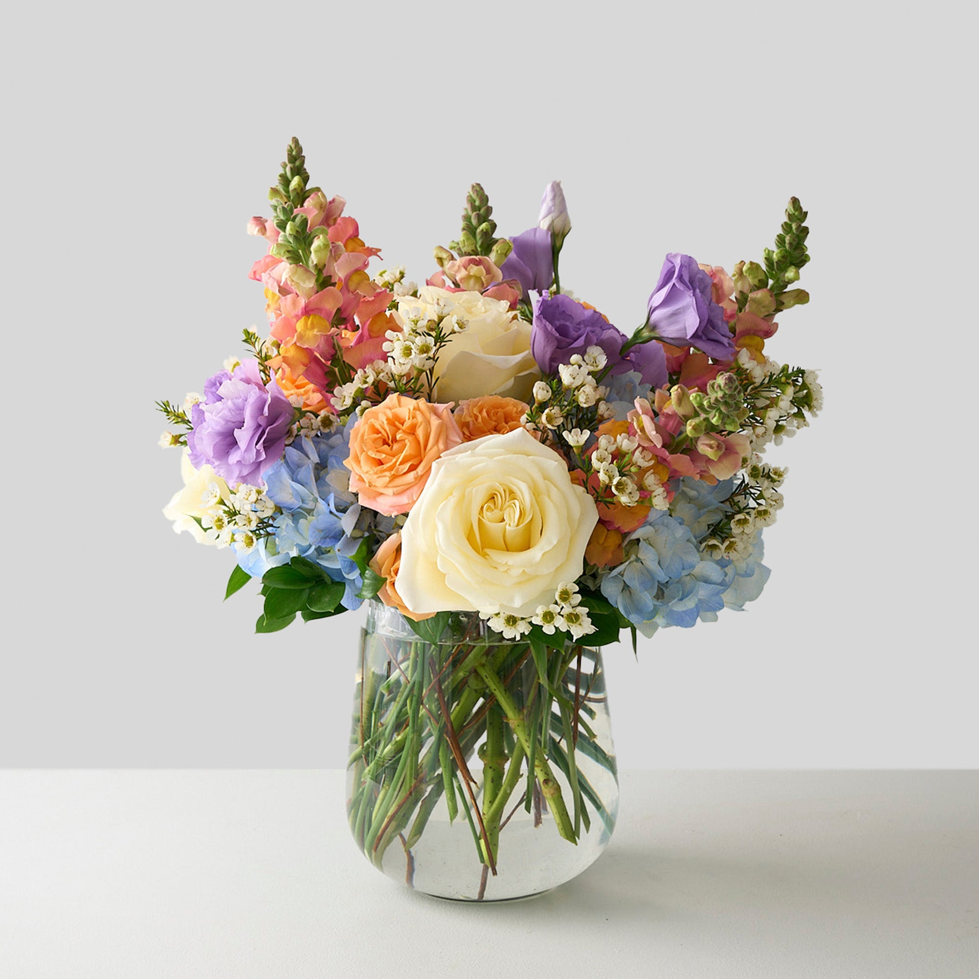 Spring flower bouquet in a clear vase on a light background