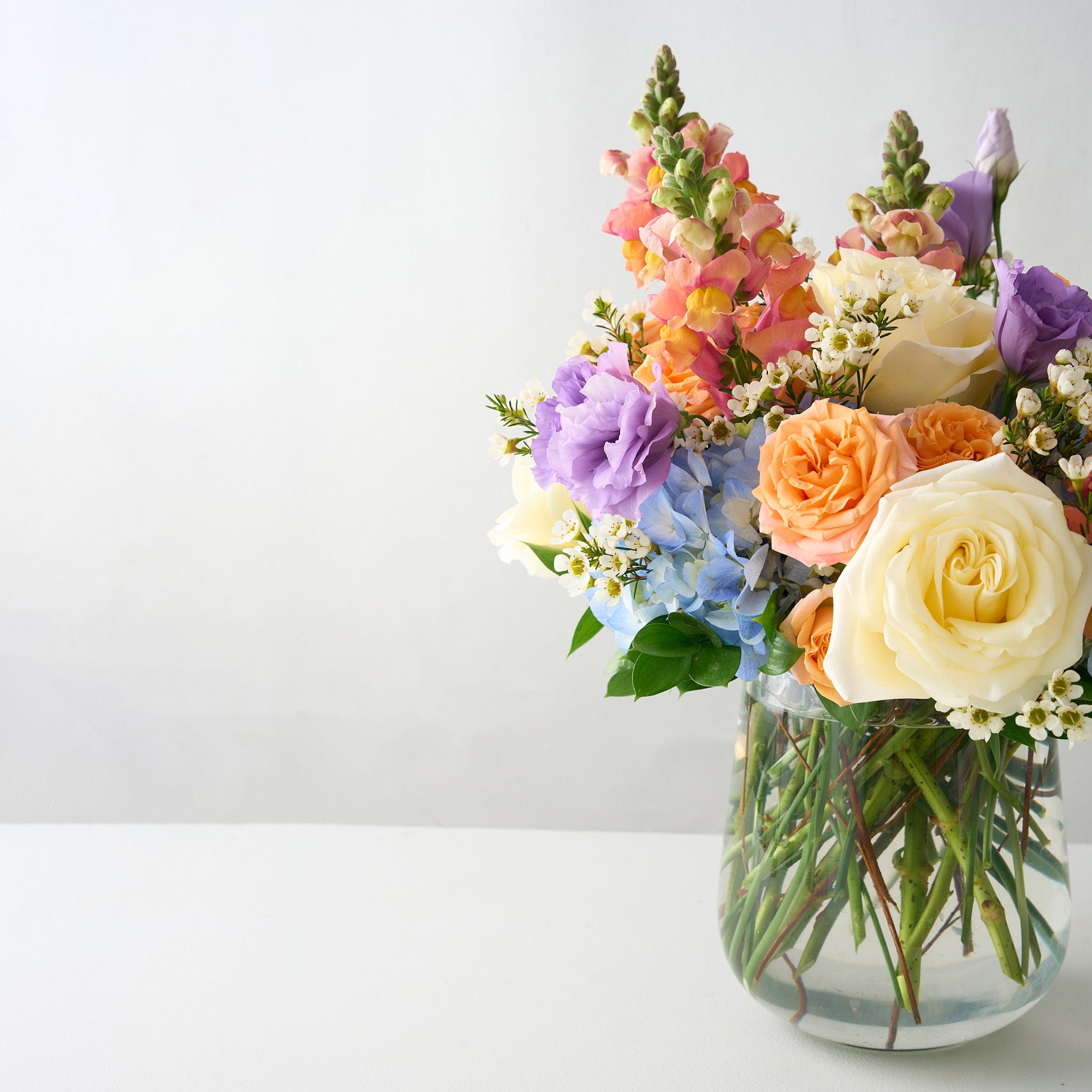 Spring flower bouquet in a clear vase on a light background