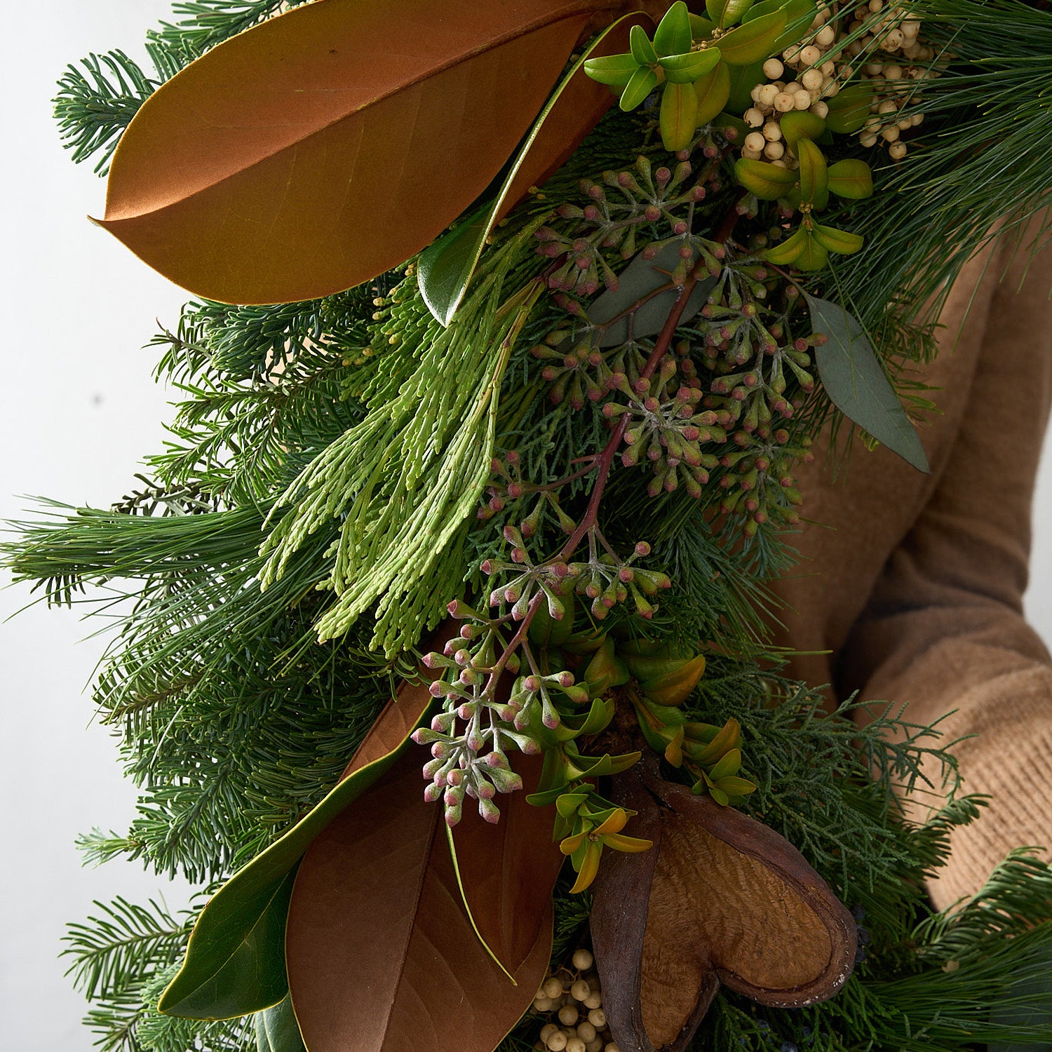close up picture of clove wreath showing brown badman pods, magnolia leaves and seeded eucalyptus