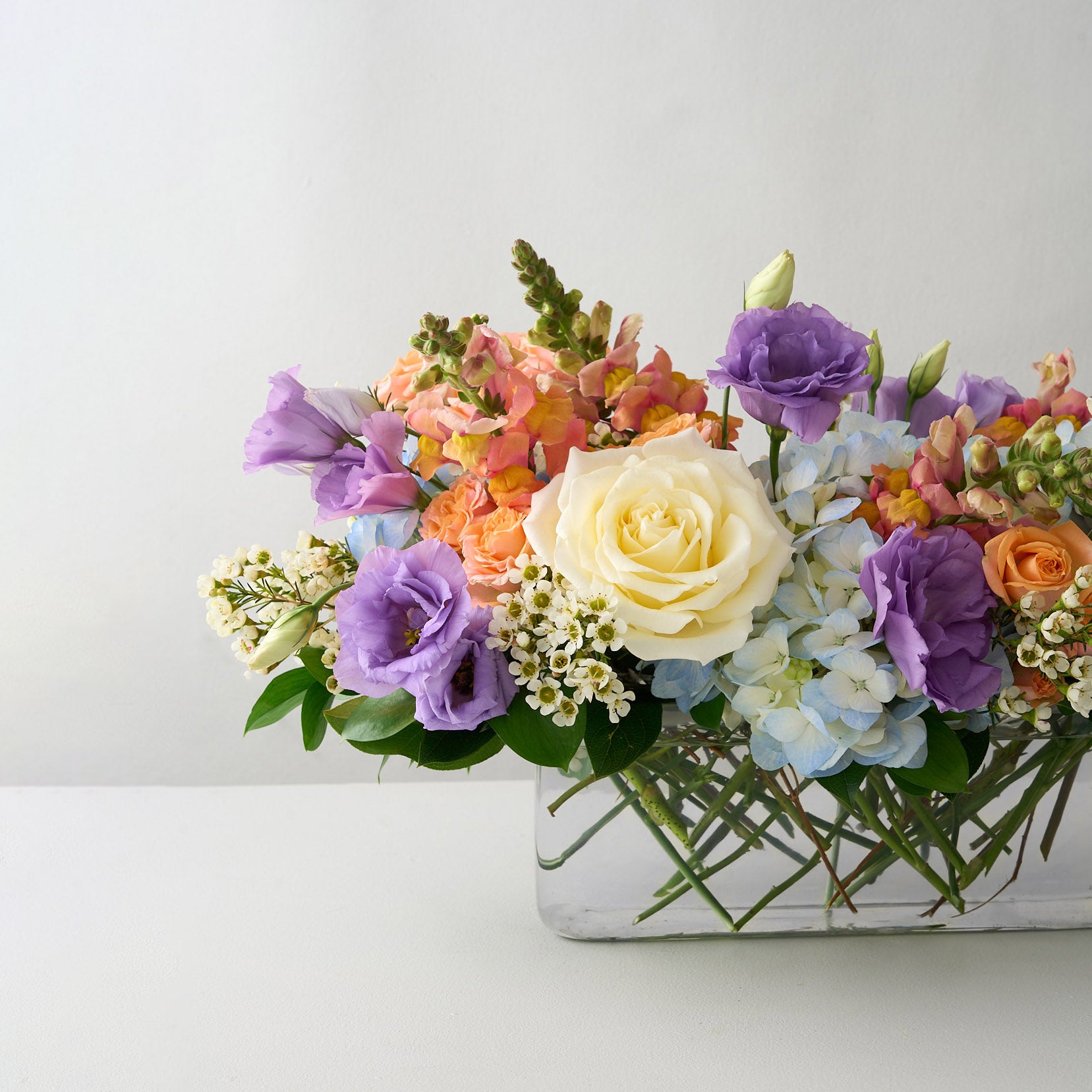 Colorful Easter floral centerpiece arrangement in a glass vase white table.