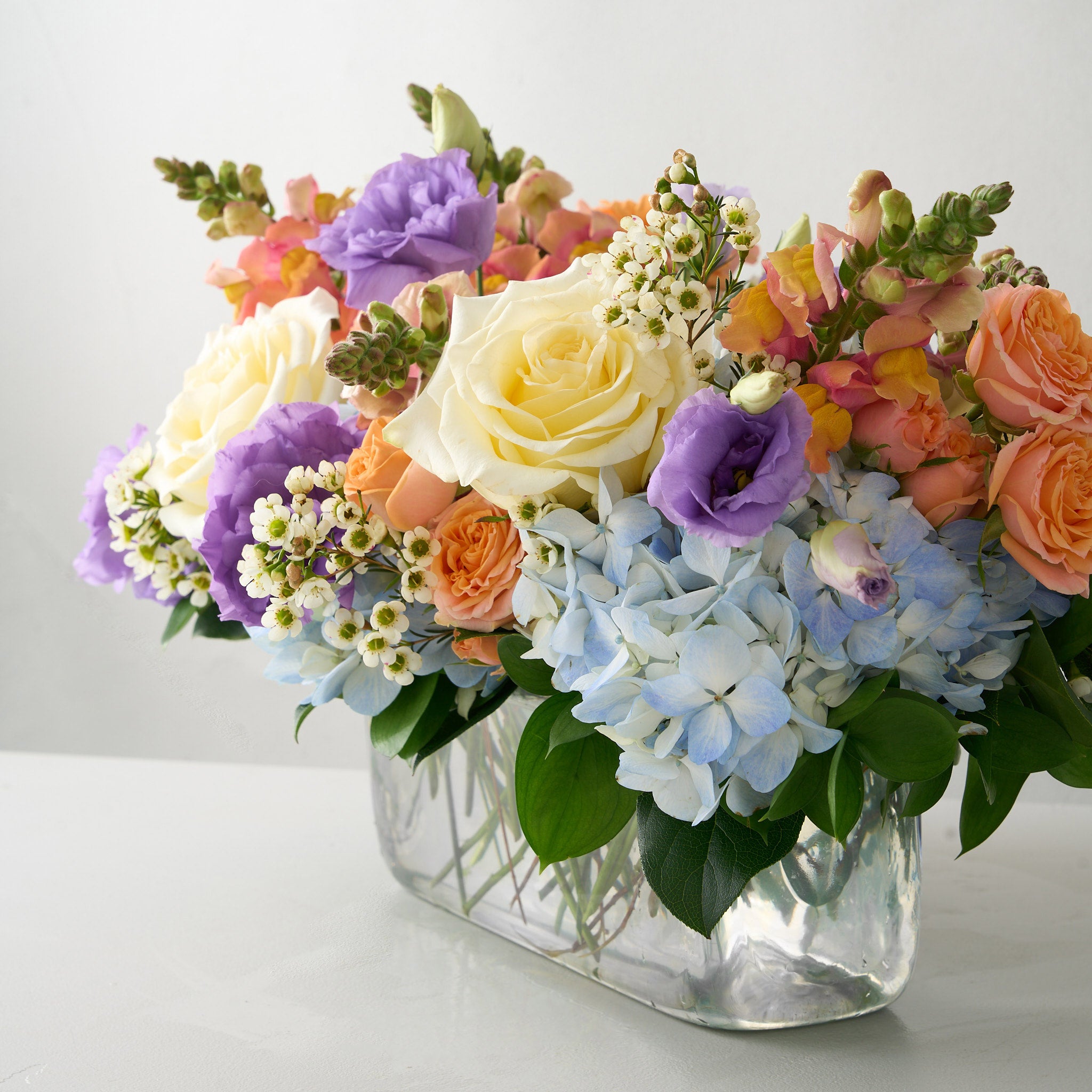 Colorful Easter floral centerpiece arrangement in a glass vase white table.