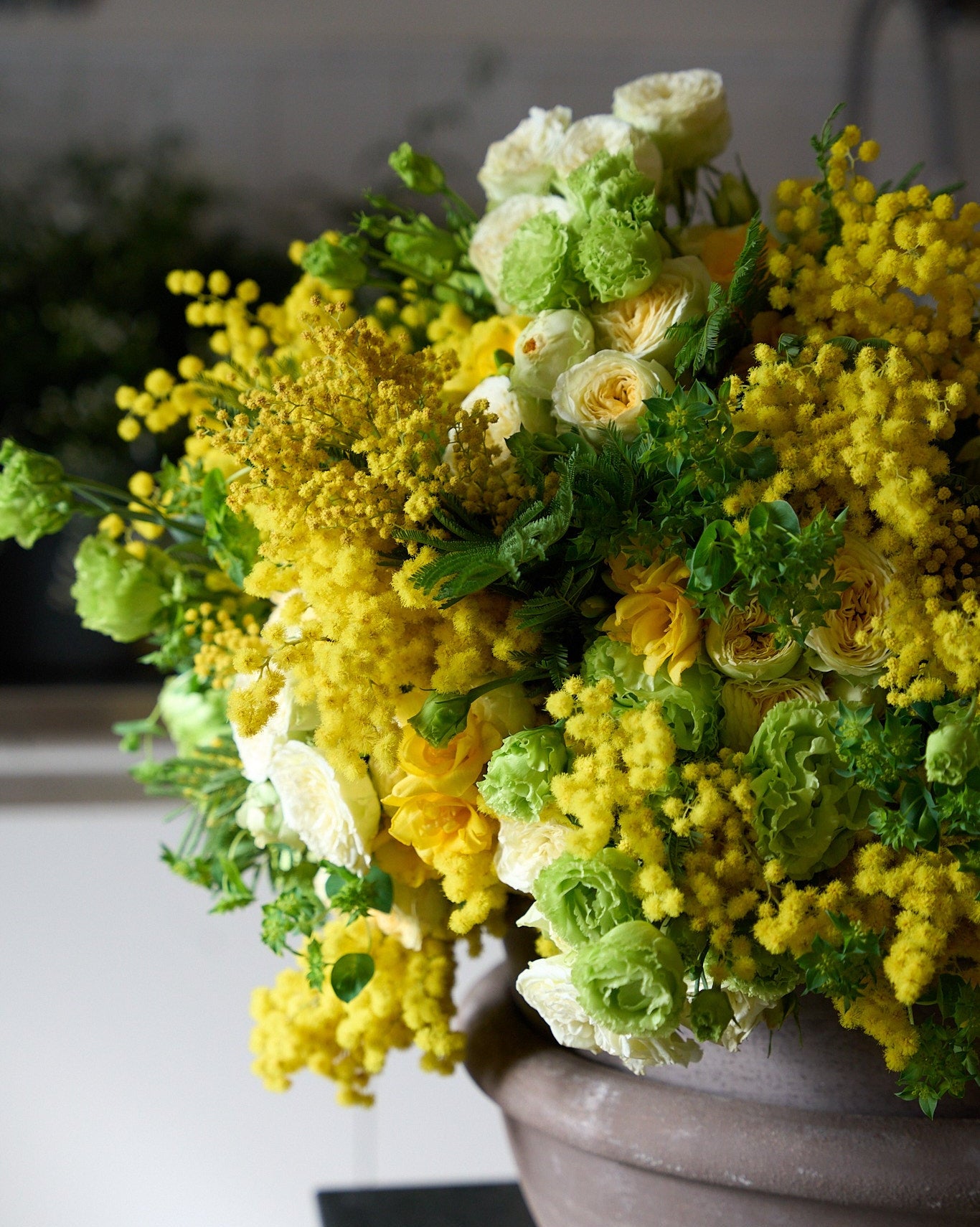 Bouquet of yellow and green flowers in a pot on a table.