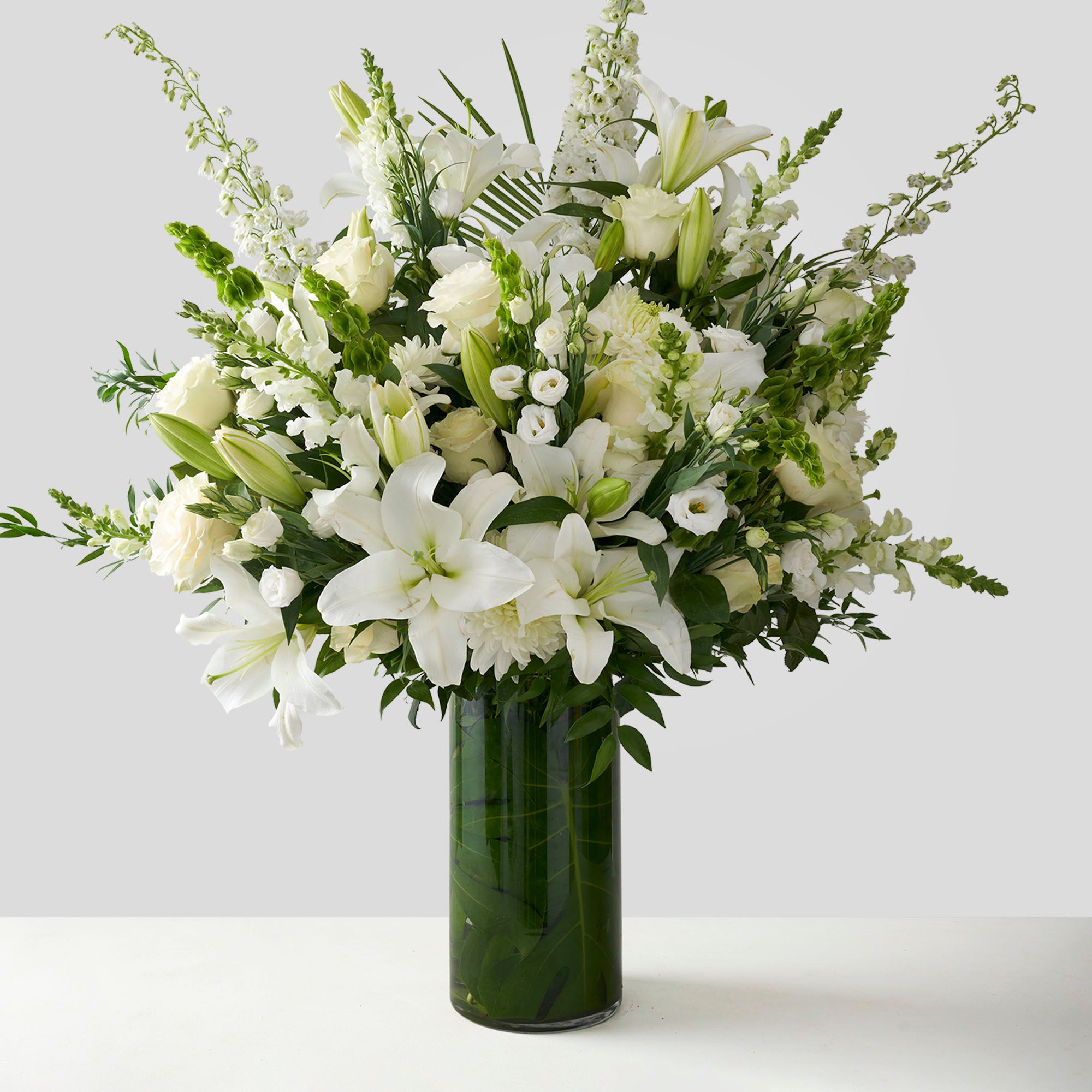 Large glass vase full of white flowers including delphinium, roses, lisianthus and lilies.