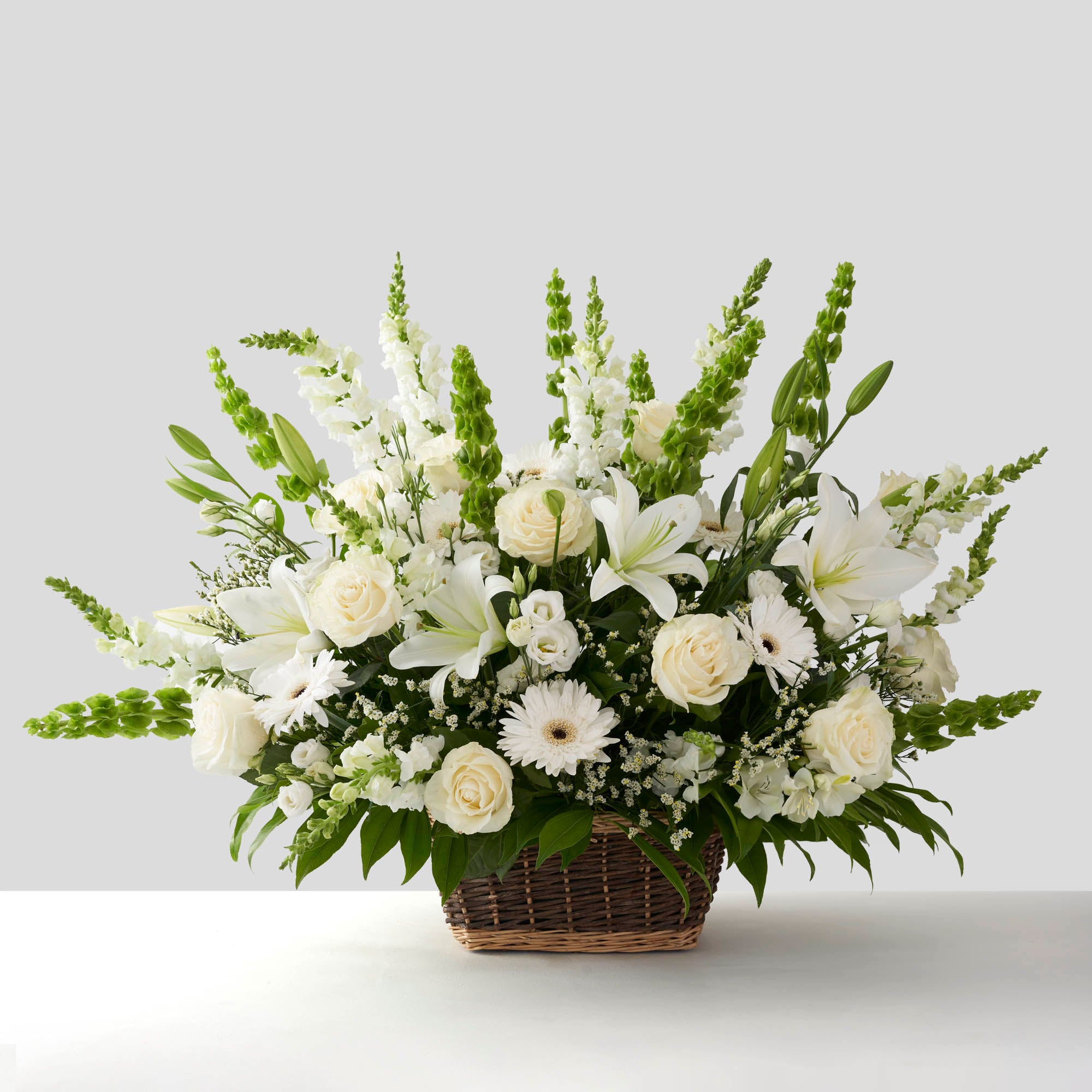 Large arrangement of all white flowers in natural basket