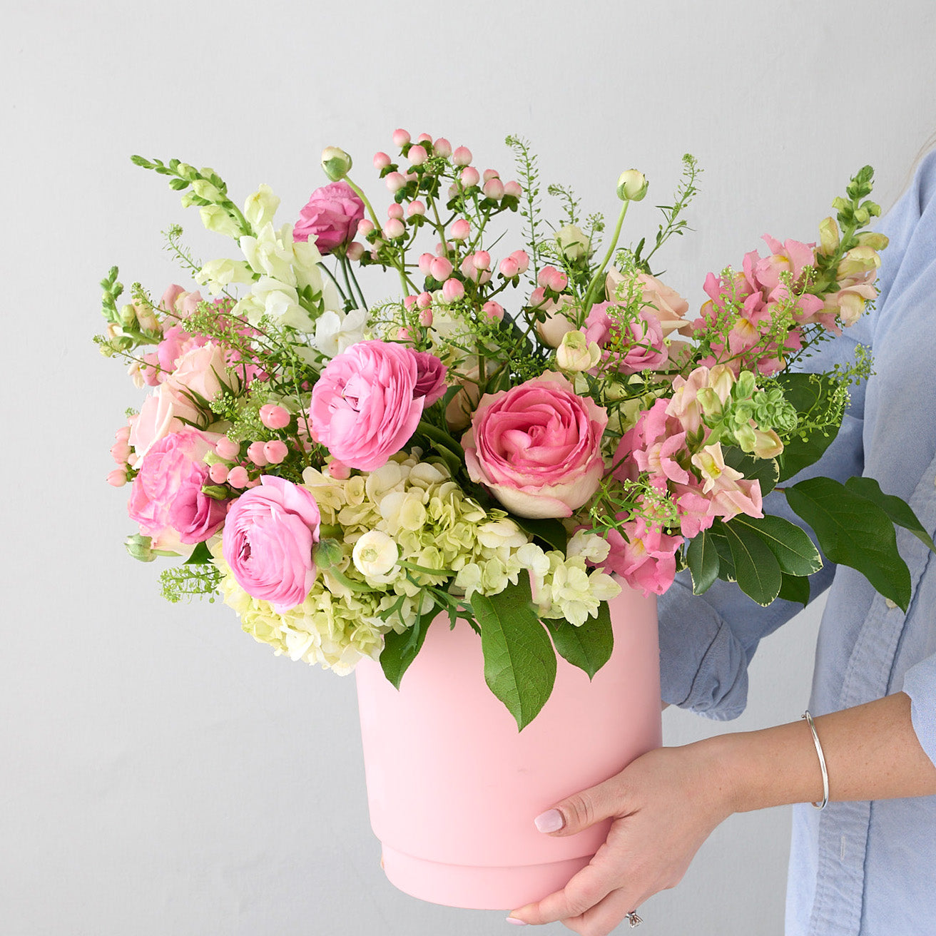 woman holding a pink vase with pink and white flowers