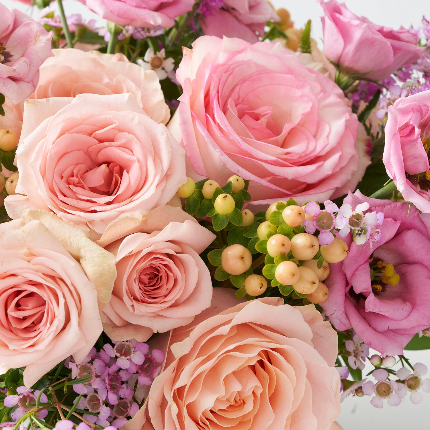  Soft peachy roses, pink wax flower, pink lisianthus and peach hypericum berries.