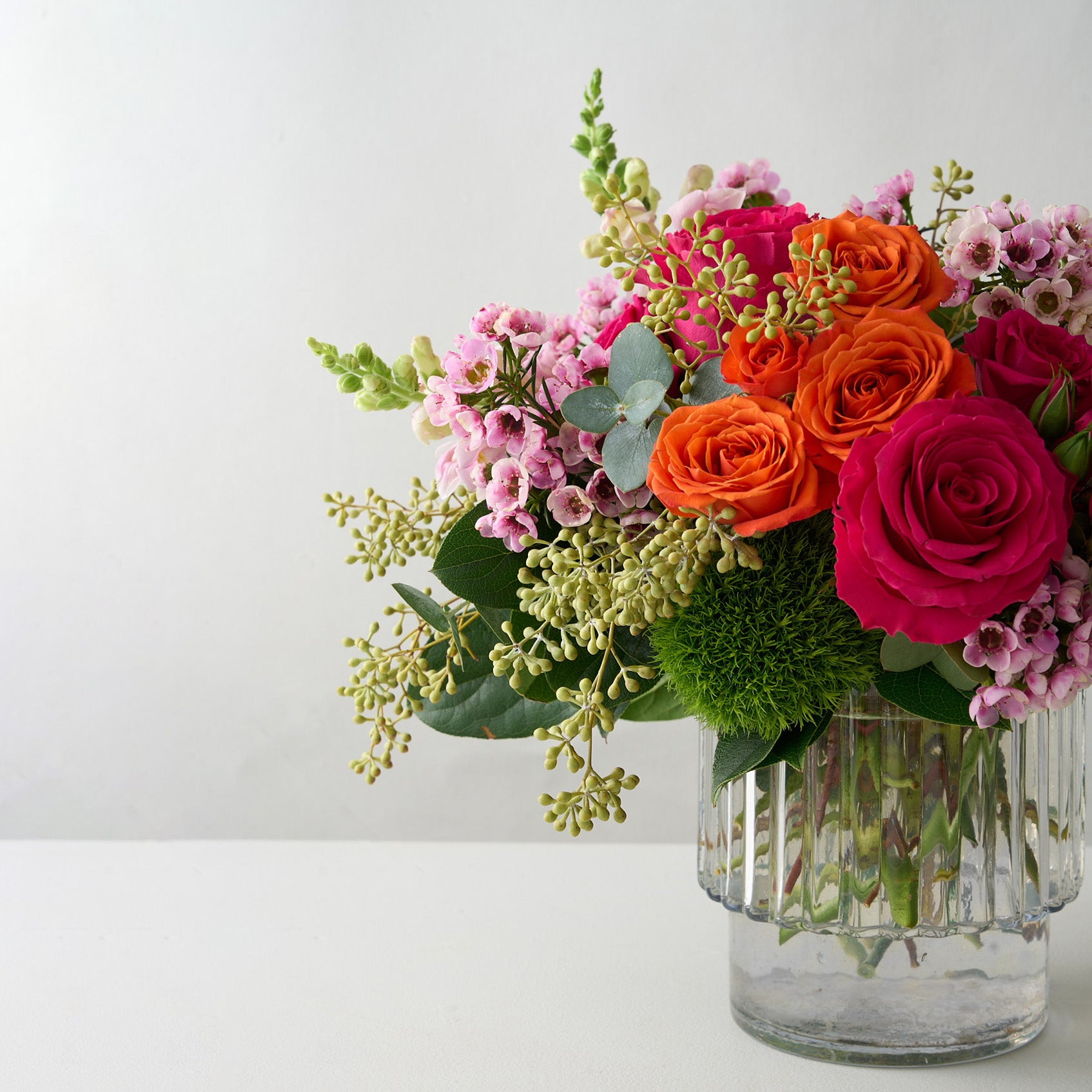 Side view of Easter flower arrangement with colorful flowers in a ribbed vase.