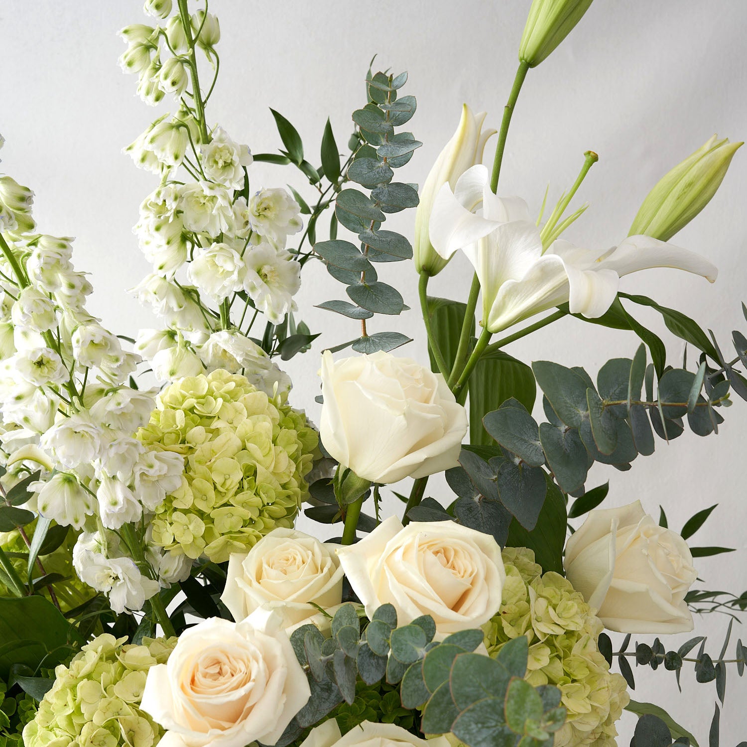 Close up view of the white roses, white lilies and green hydrangea