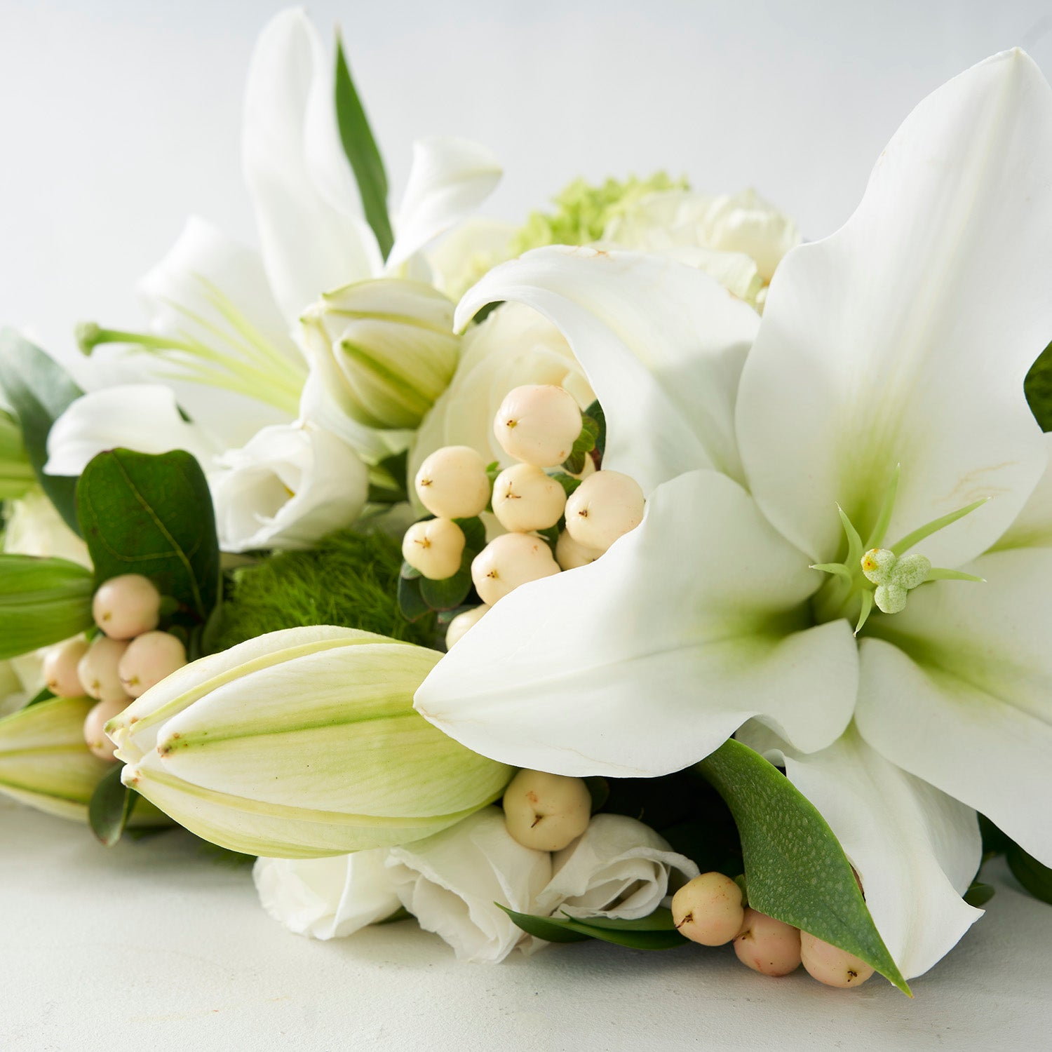 Closeup of white lilies and cream hypericum berries.