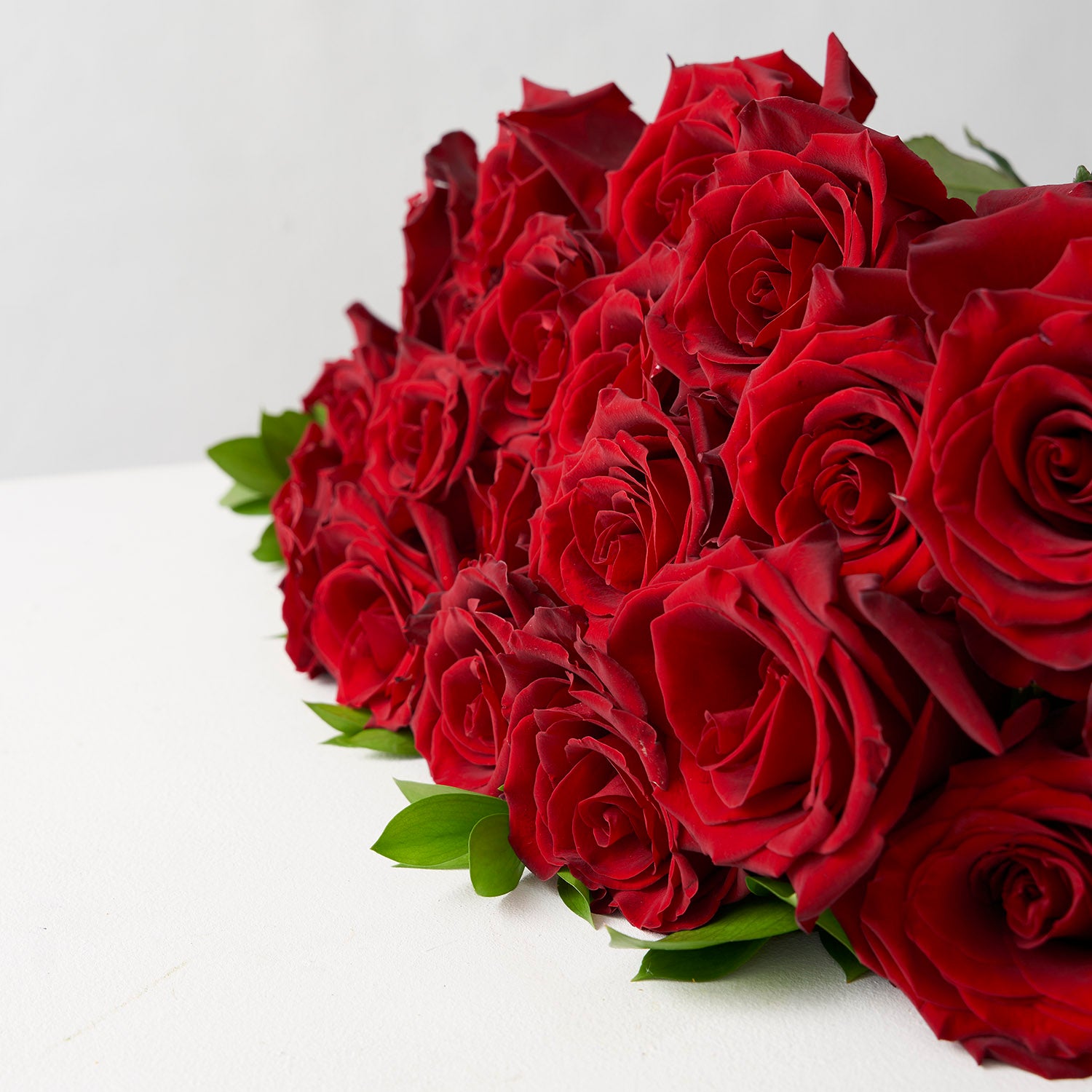Close up of an assortment of deep red roses placed on a white table