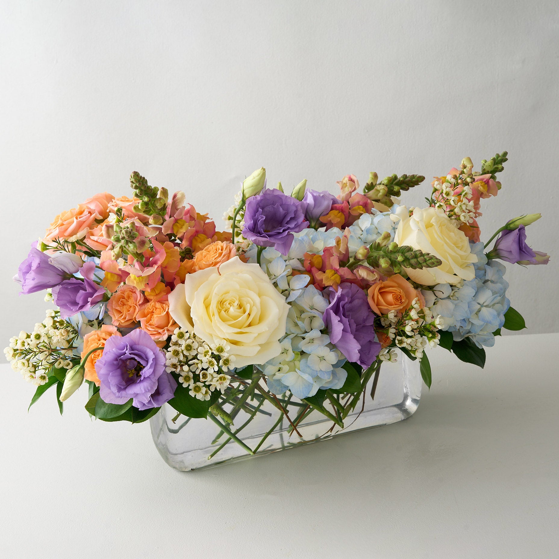Colorful Easter floral centerpiece arrangement in a glass vase white table.