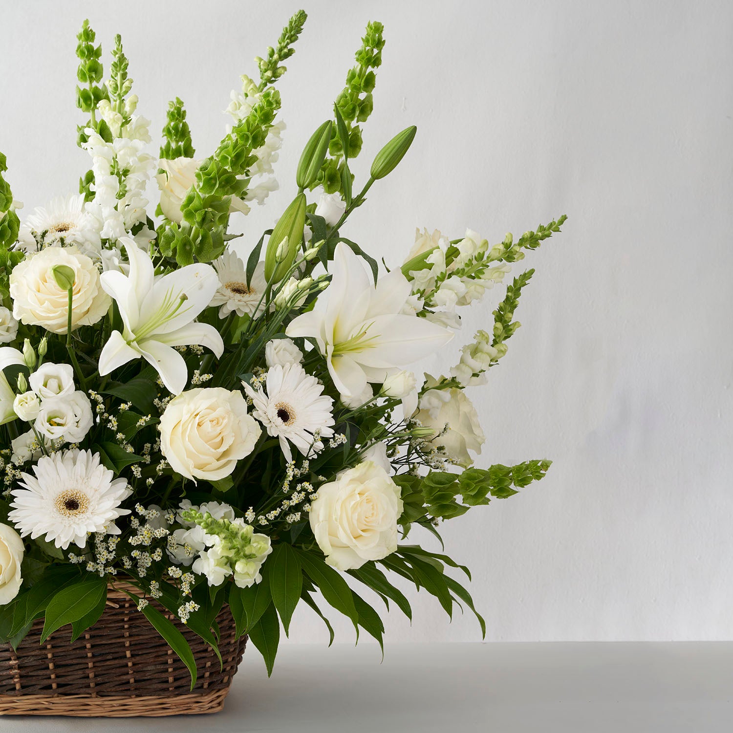 Natural basket filled with white flowers arranged in a spray.
