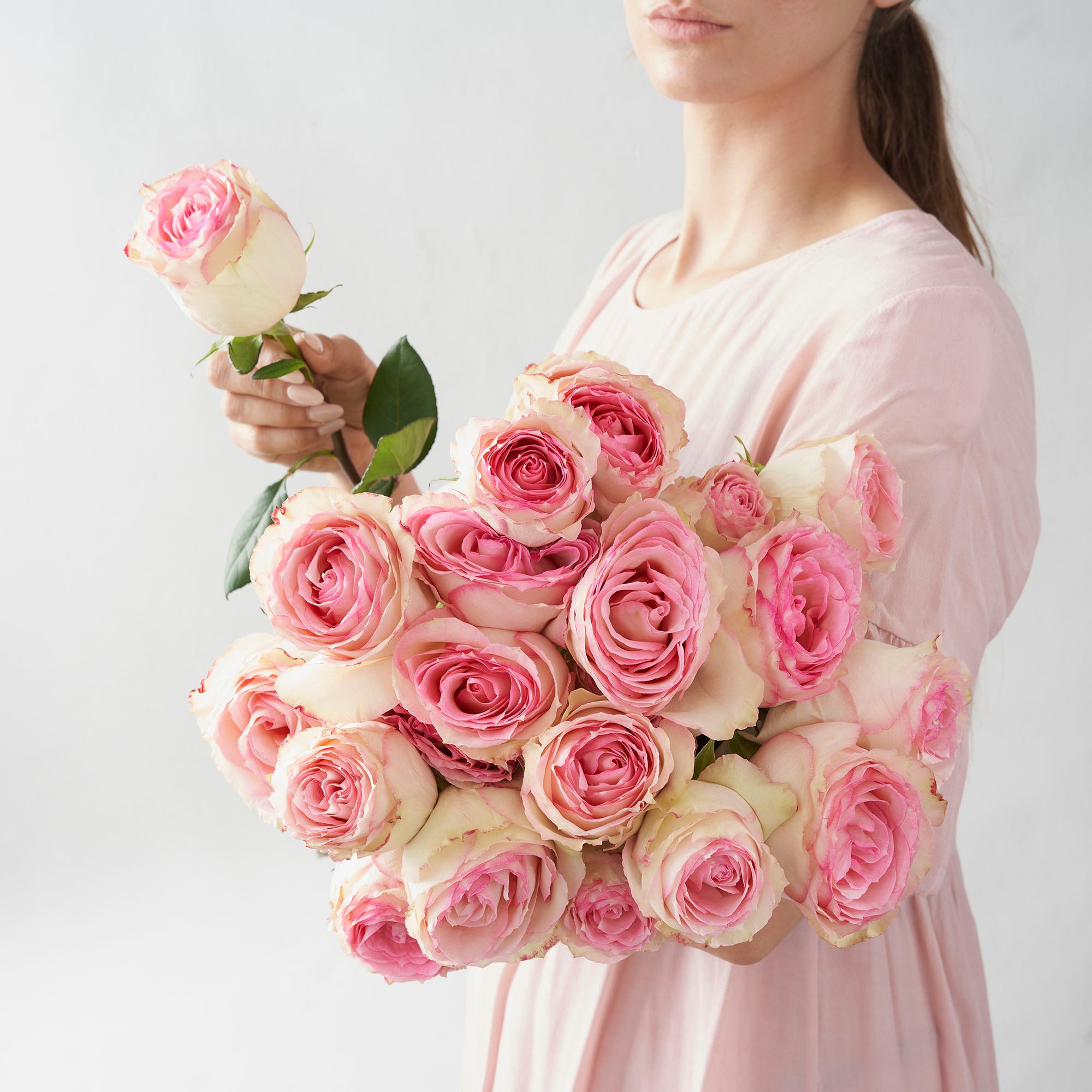 Woman in pink shirt holding large bouquet of pink Esperance roses.