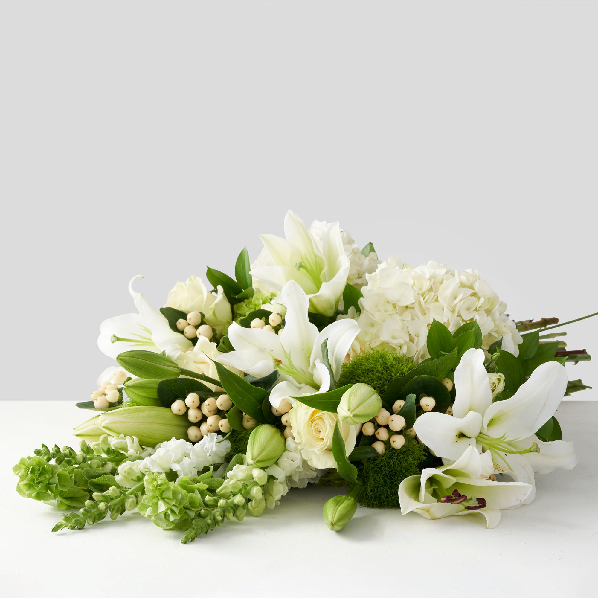 Large bouquet of white and green flowers on white background.