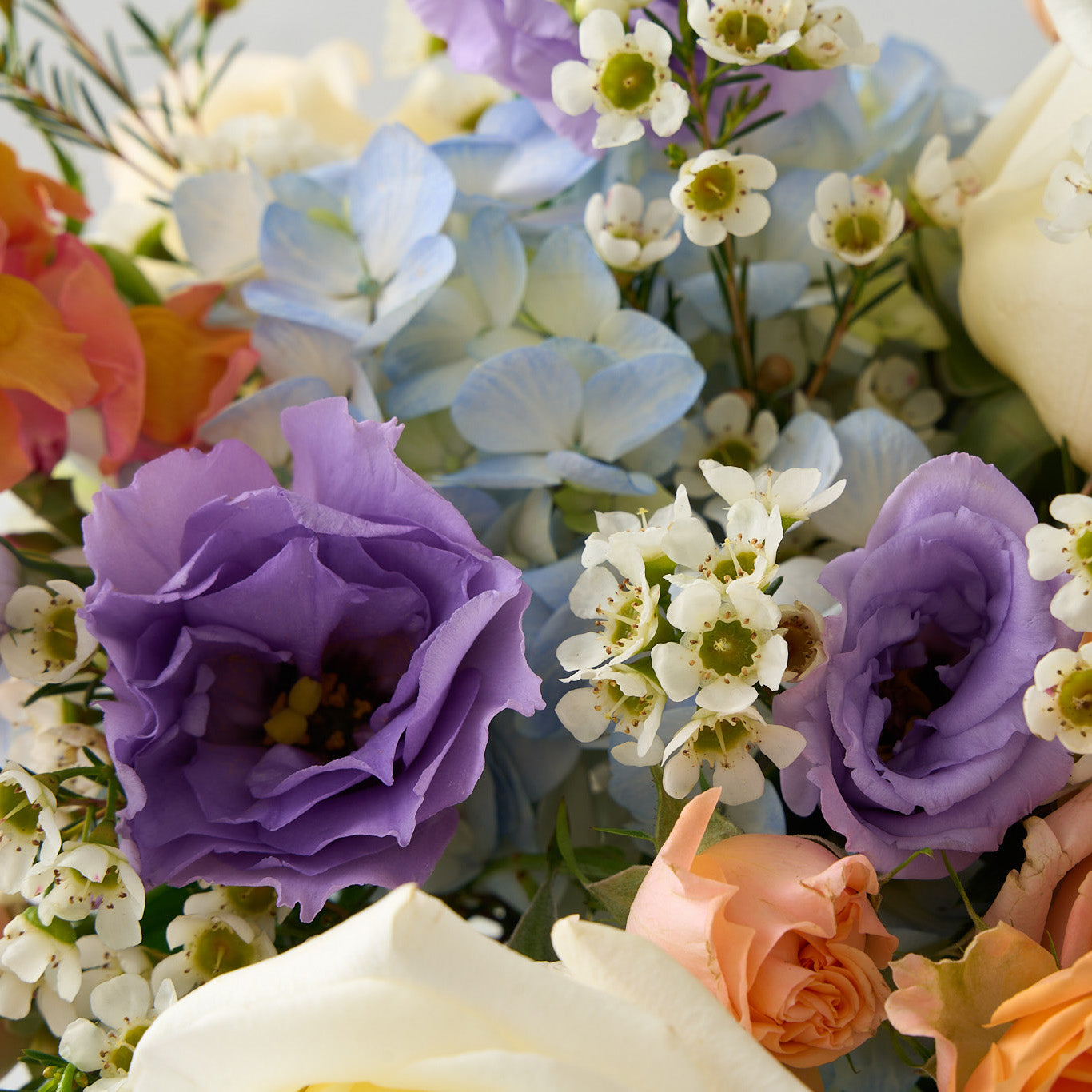 close up photo of Easter and passover flower arrangement with peach, cream, blue and purple flowers.