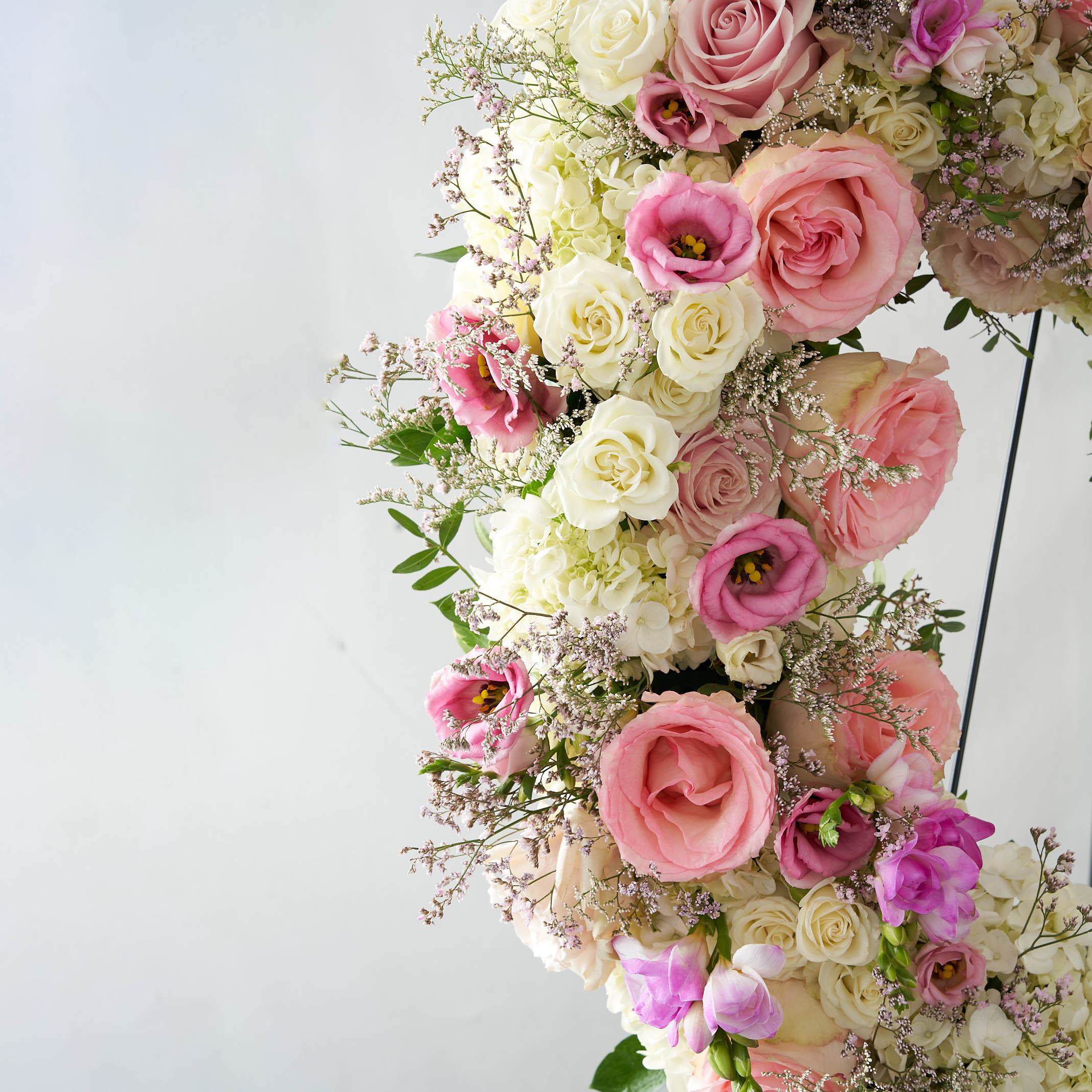 Pink and white roses and lisianthus, as well as sprigs of baby's breath and green foliage.