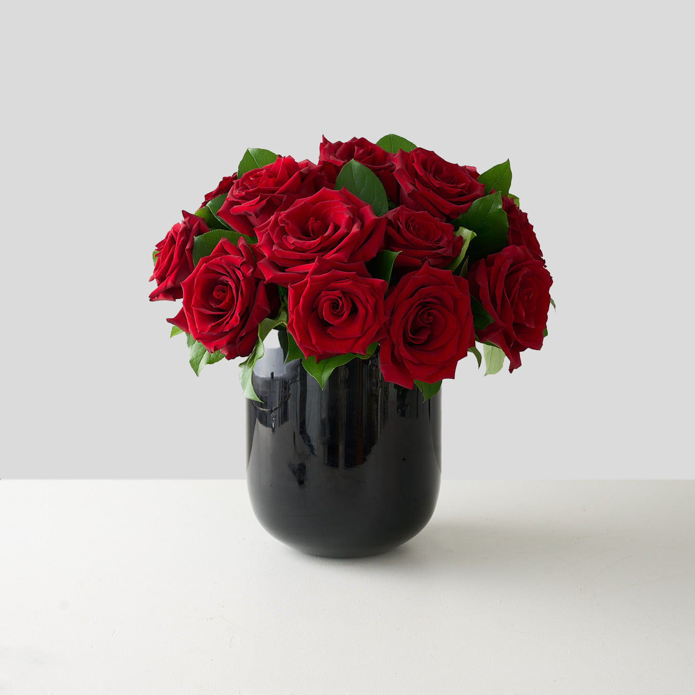 Black vase with red roses on a white background