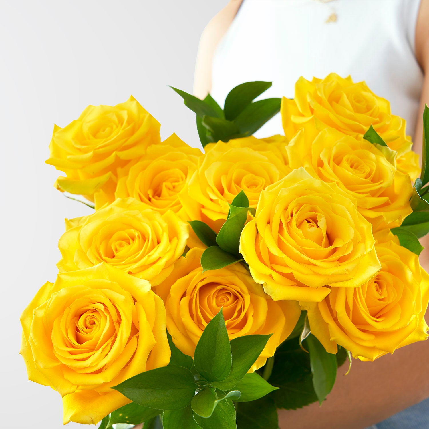 Close up of yellow roses, there is a blurry person holding them.