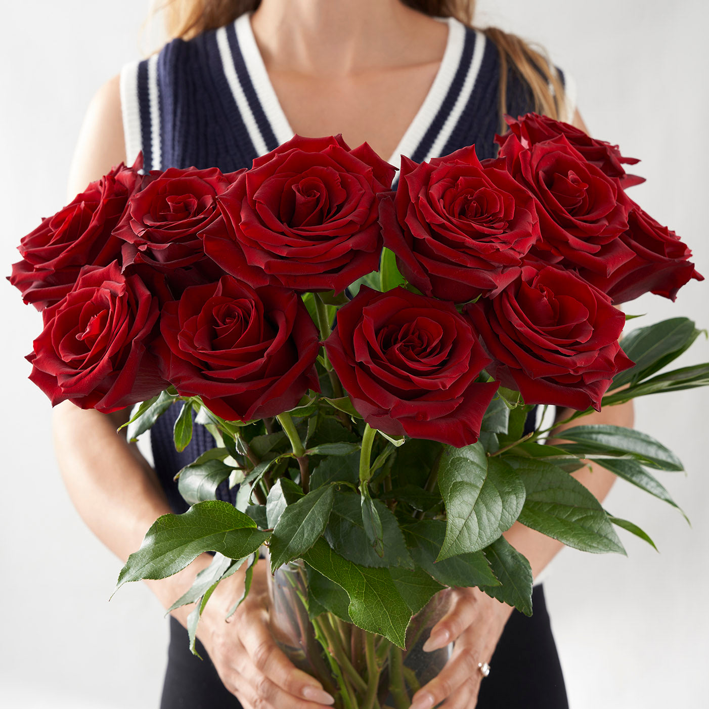 Woman holding vase full of red roses.