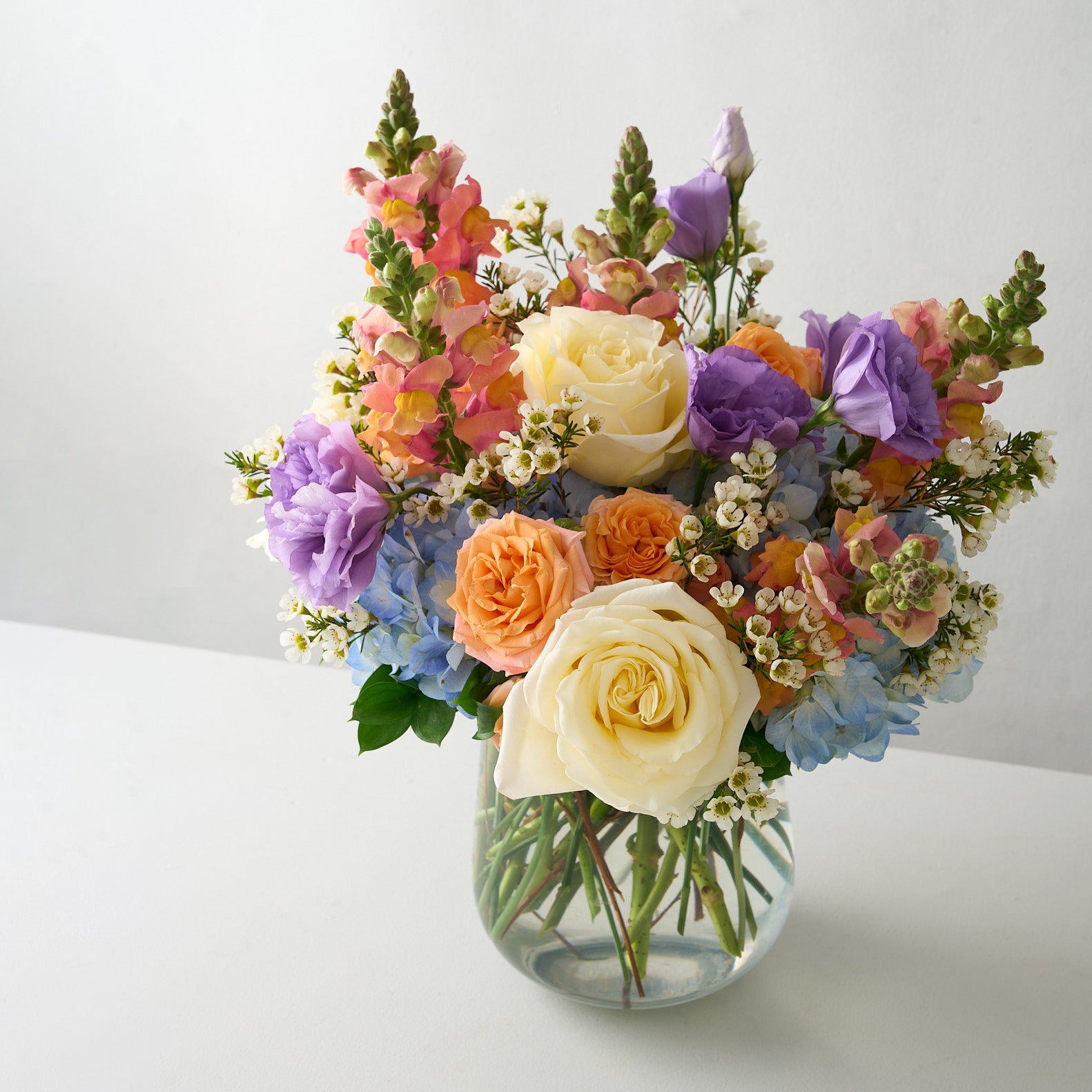 close up photo of Spring flower bouquet in a clear vase on a white table