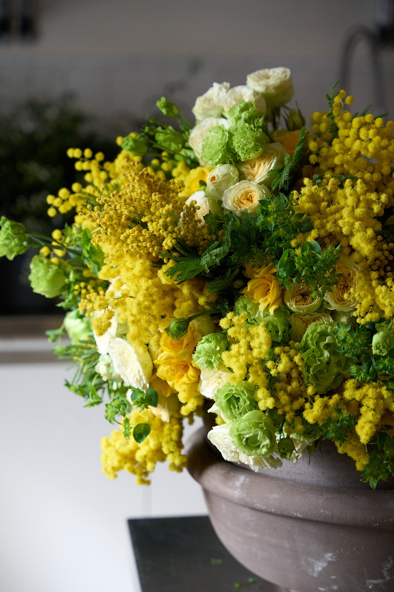 Bouquet of yellow and green flowers in a pot on a table.