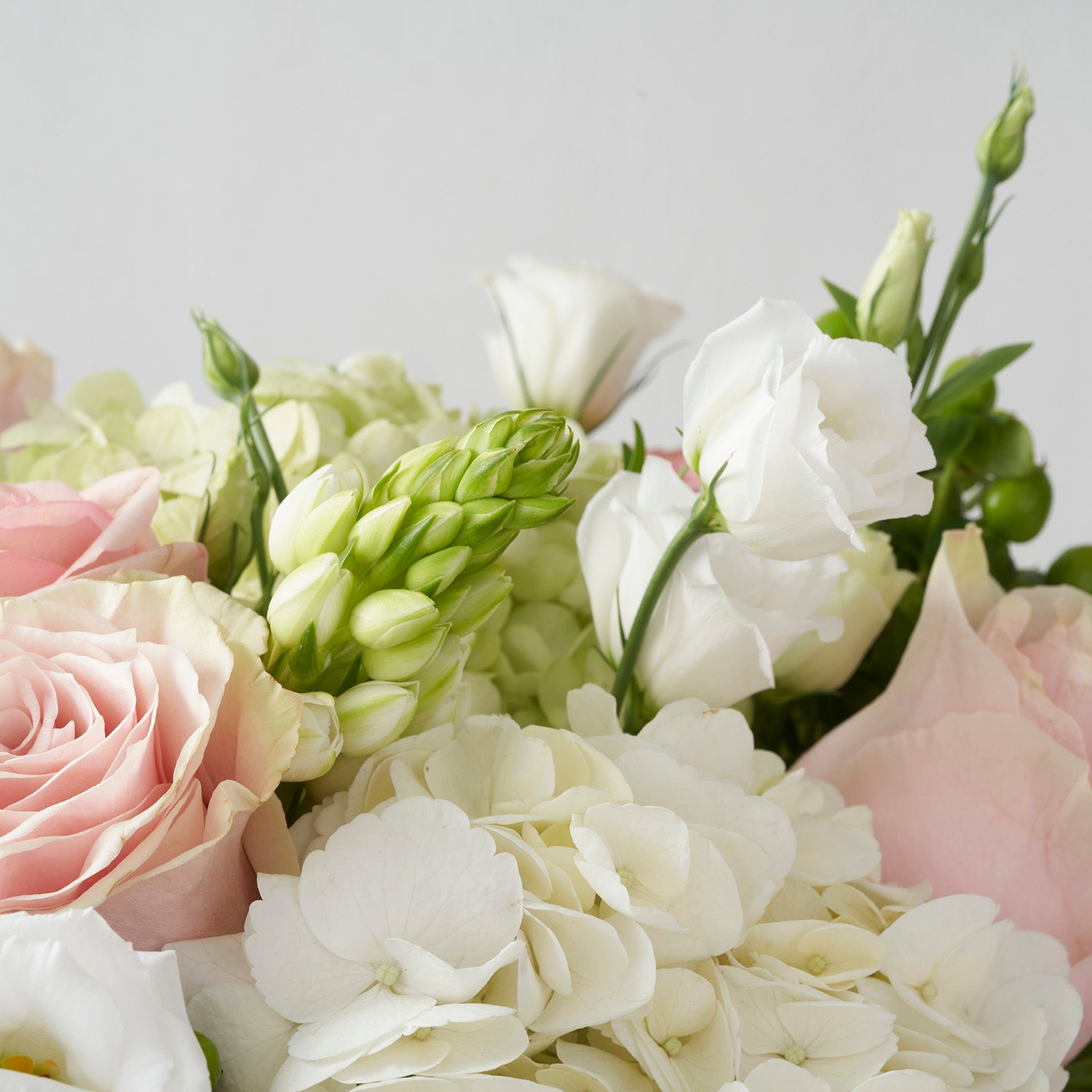 Closeup of pink Mondial roses, white hydrangea, and white lisianthus flowers.