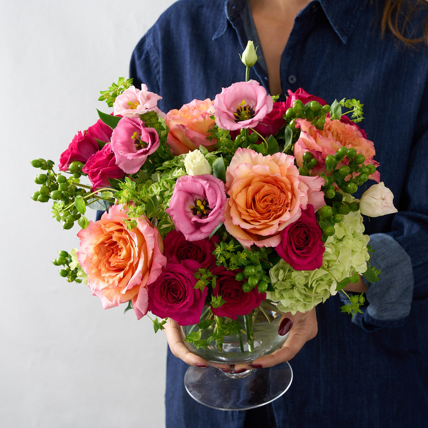 woman holding an arrangement of a vibrant mix of Freespirit roses, fuchsia, pinks, and greens would give off an energetic, joyful, and playful vibe