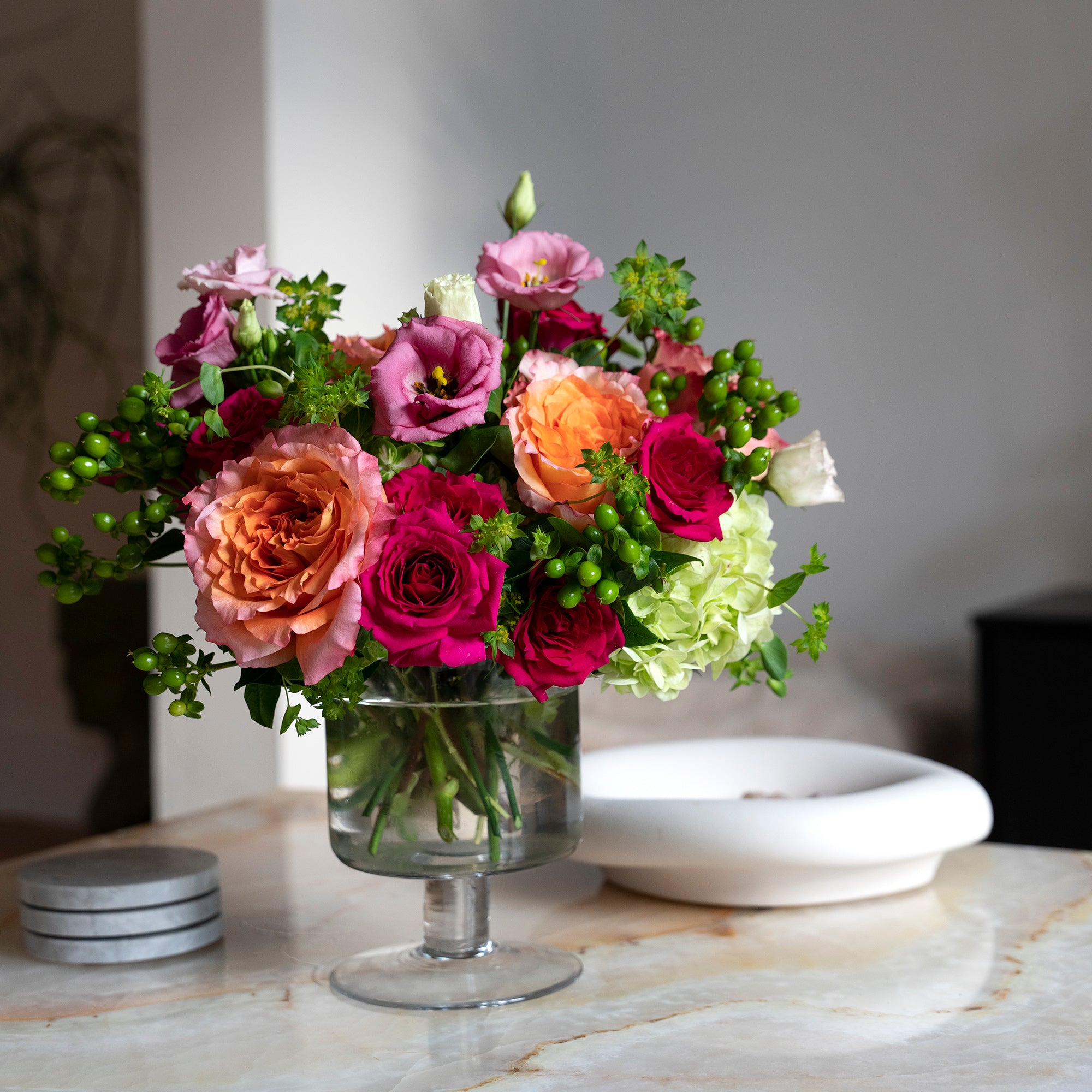 An arrangement of a vibrant mix of Freespirit roses, fuchsia, pinks, and greens that has an energetic, joyful, and playful vibe in home setting