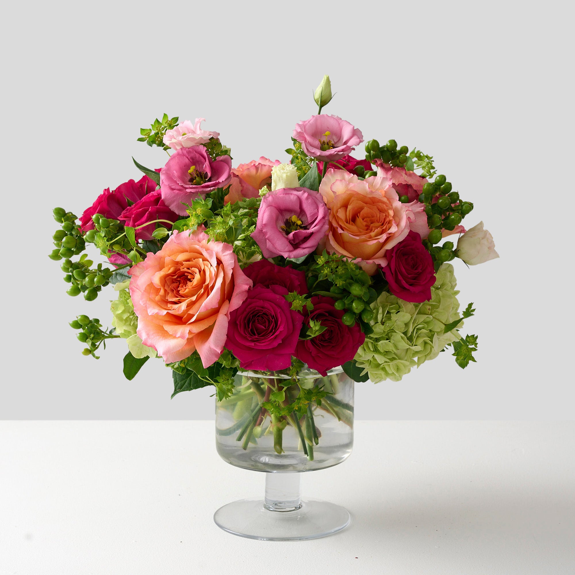 An arrangement of a vibrant mix of Freespirit roses, fuchsia, pinks, and greens would give off an energetic, joyful, and playful vibe