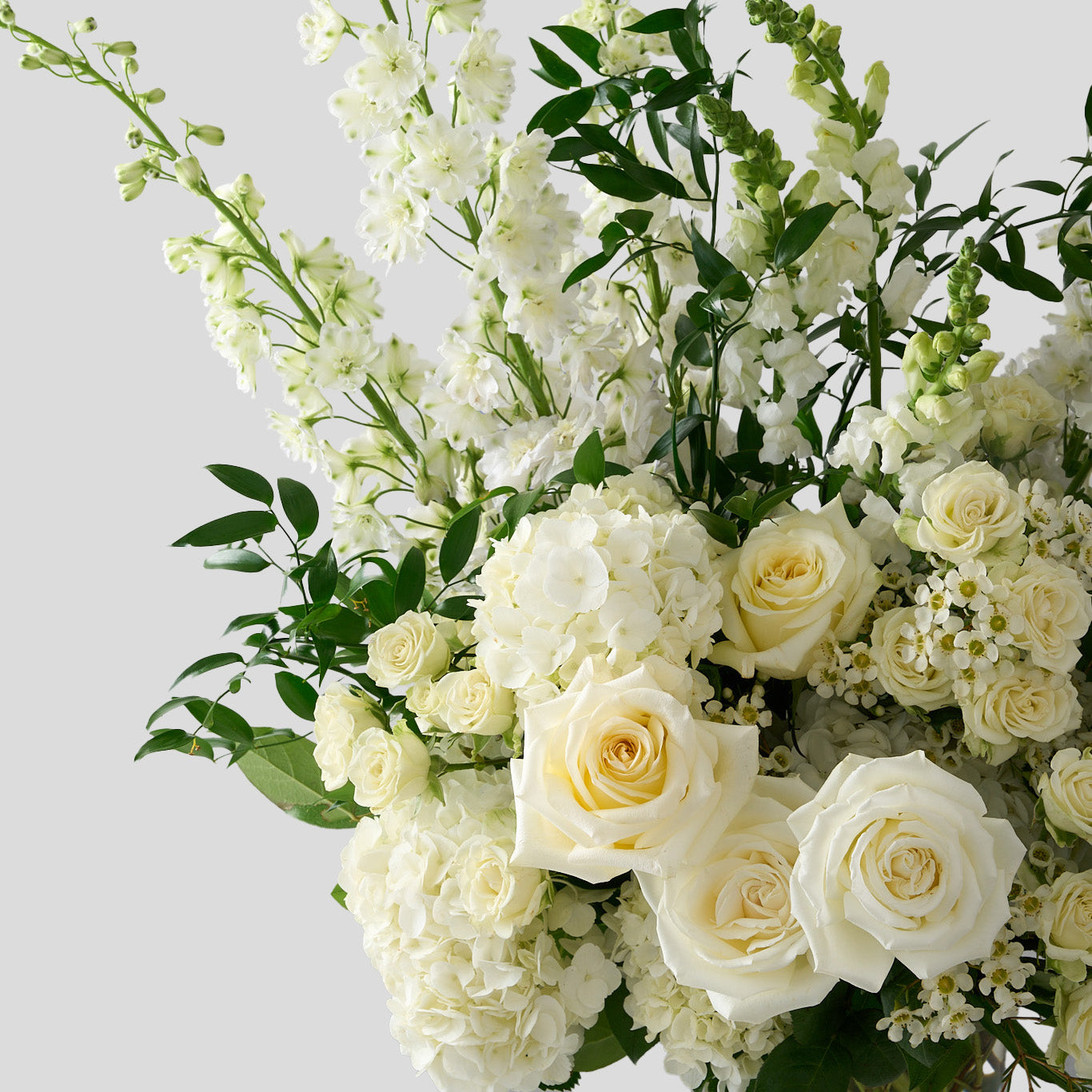 creative photo zoomed in to show Candlelight roses, white delphiniums and hydrangeas with whimsical Italian ruscus. 