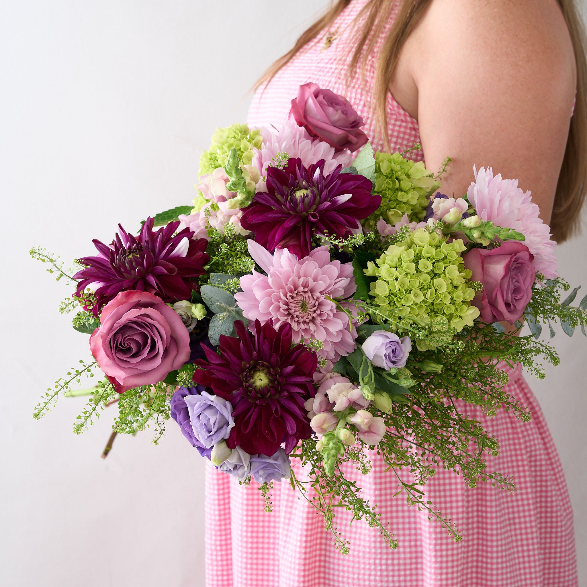 Bouquet of purple, pink dahlias, mauve long stemmed roses green  hydrangea and lavender Lisianthus on a light gray background