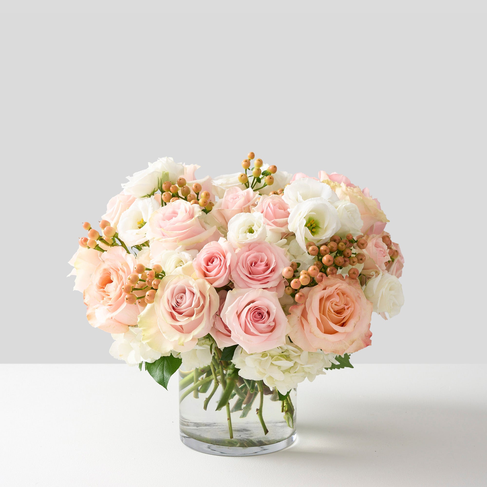  pink roses, peach hypericum, white hydrangea in a clear cylinder vase