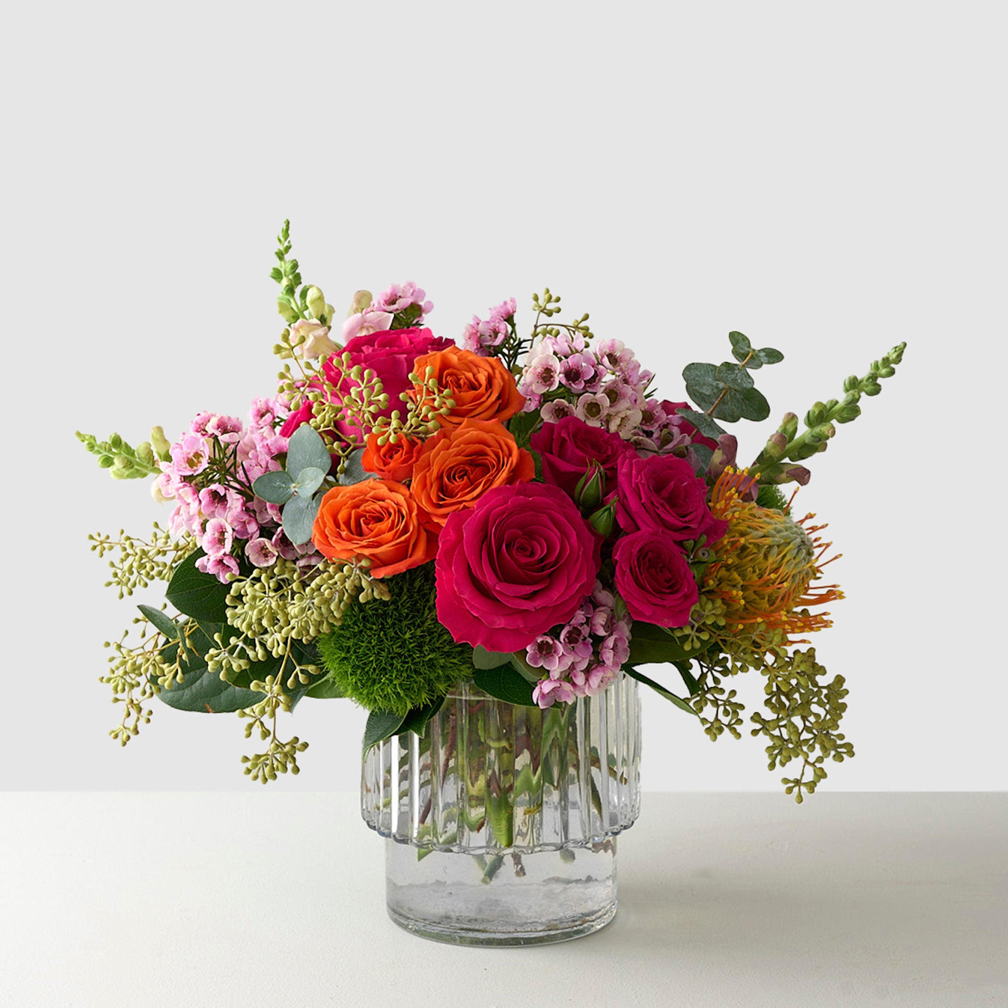 Easter flower arrangement with colorful flowers in a ribbed vase.