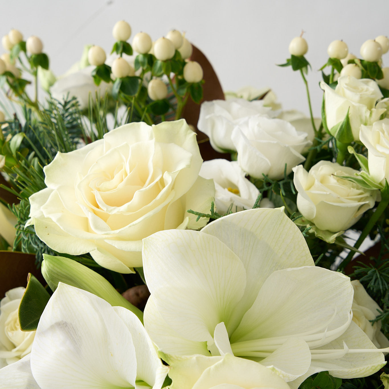 up close picture of white roses, lisianthus, hypericum arrangement