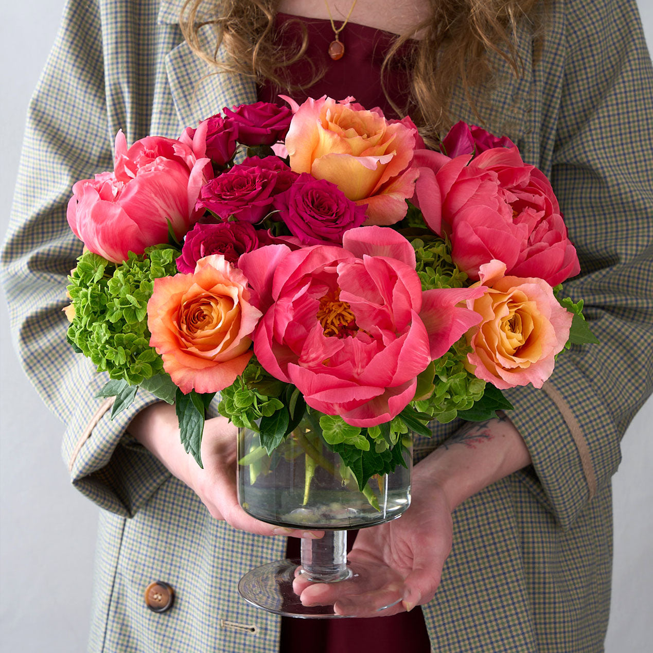 Woman in coat holding the eva arrangement in a glass vase