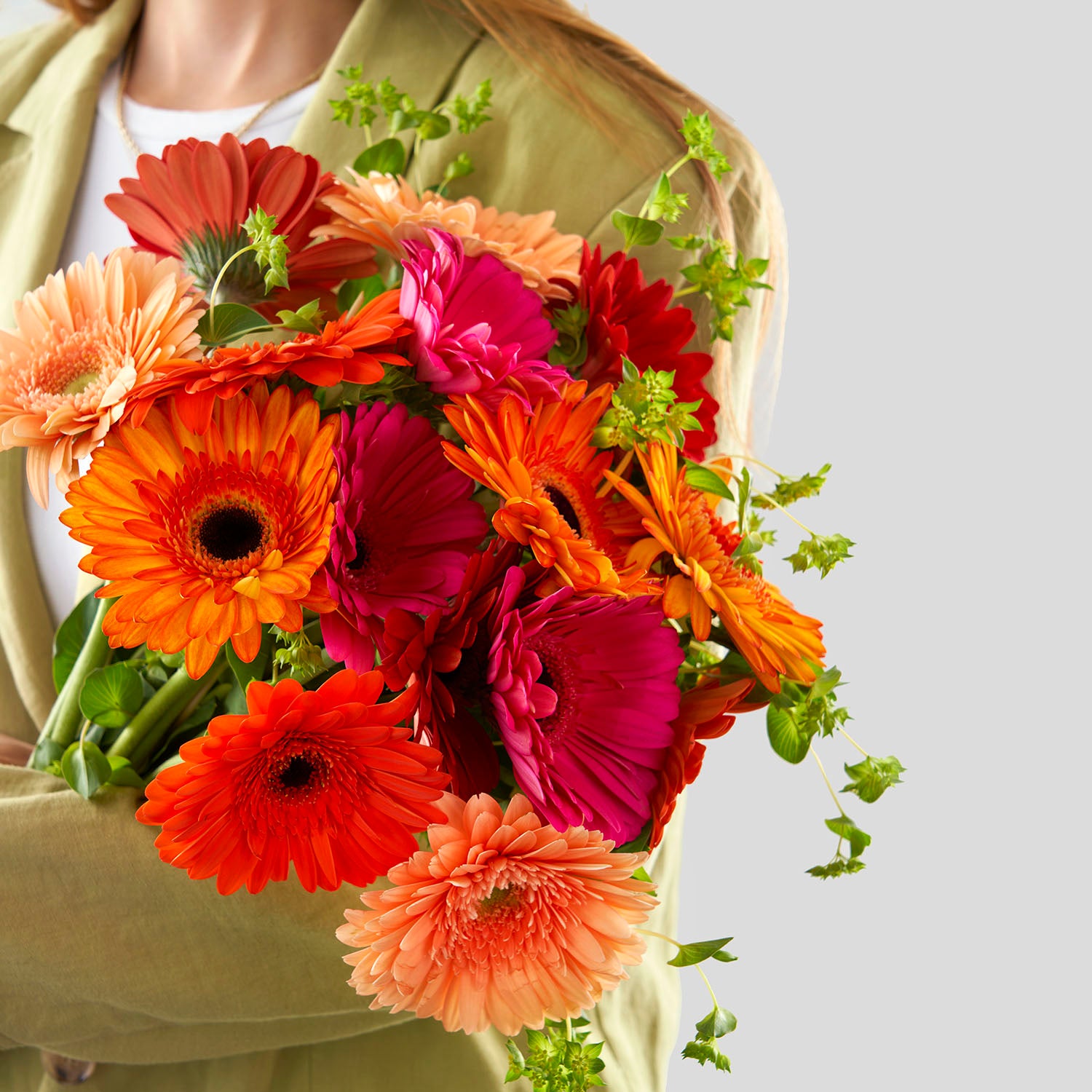 Woman in green shirt holding bouquet of gerberas,