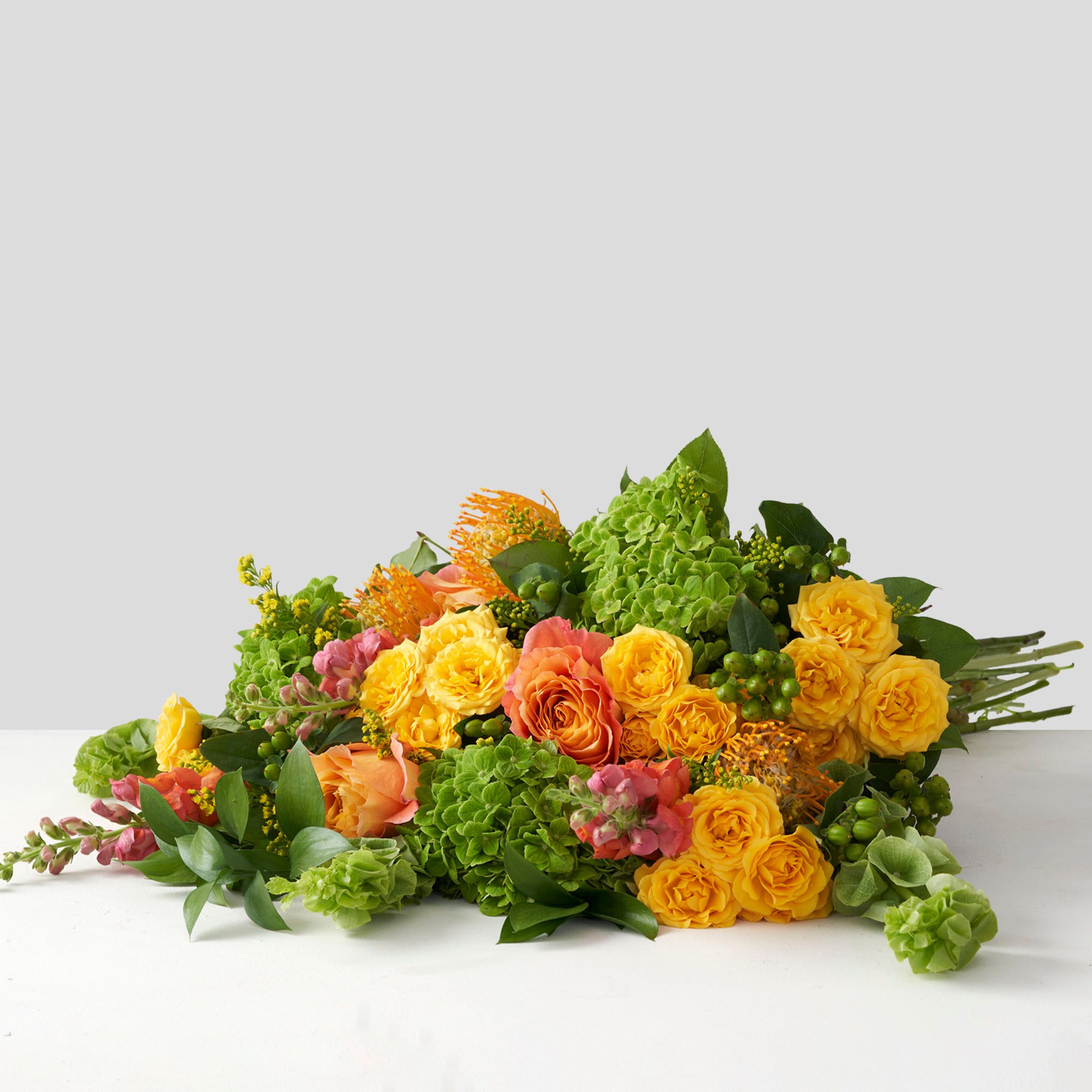 Large bouquet of yellow, lime green, and orange flowers on white background. 