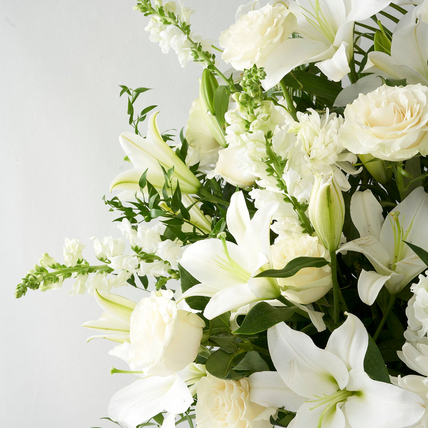 Closeup of white flowers including snapdragons, lilies, and roses.