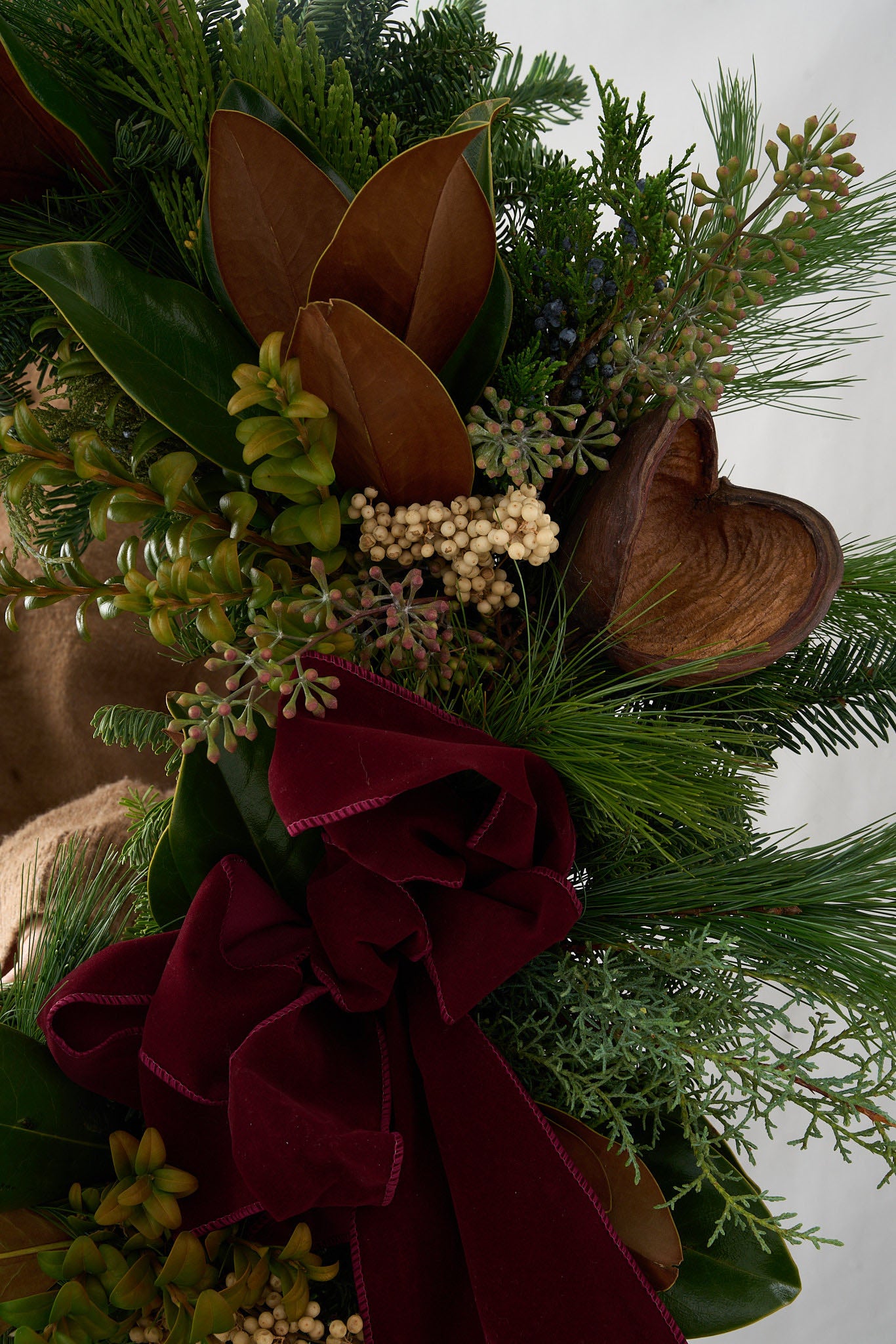 up close shot of holiday wreath with badman pods, white peppercorn, boxwood ,seeded eucalyptus, cedar and white pine greens