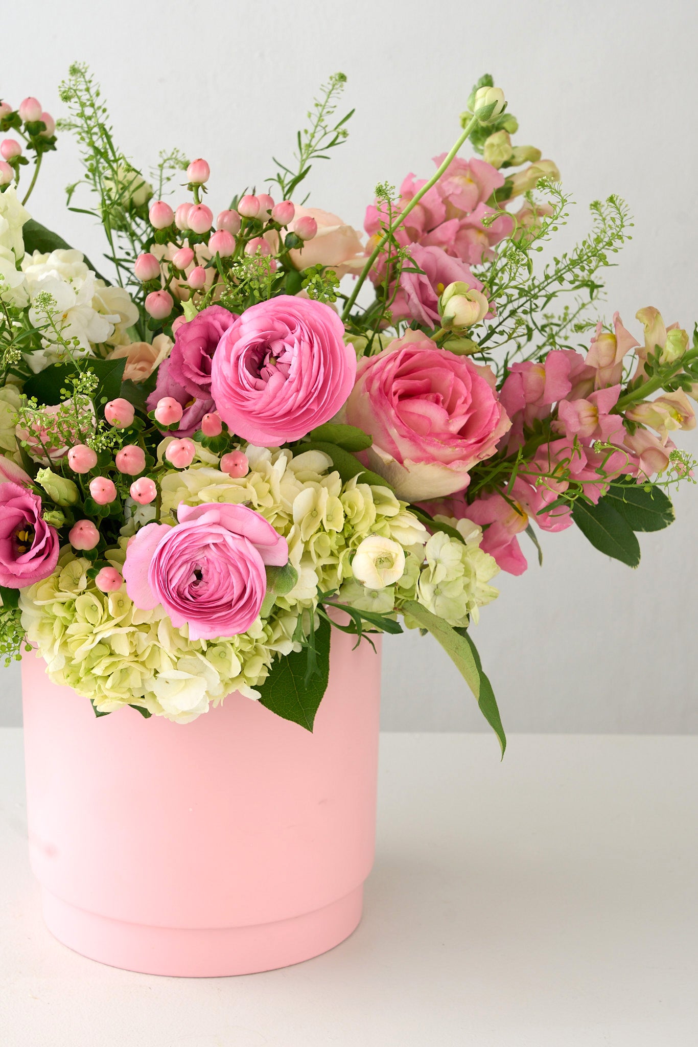 Pink vase with white, pink and green snapdragons, hydrangea, ranunculus, roses 