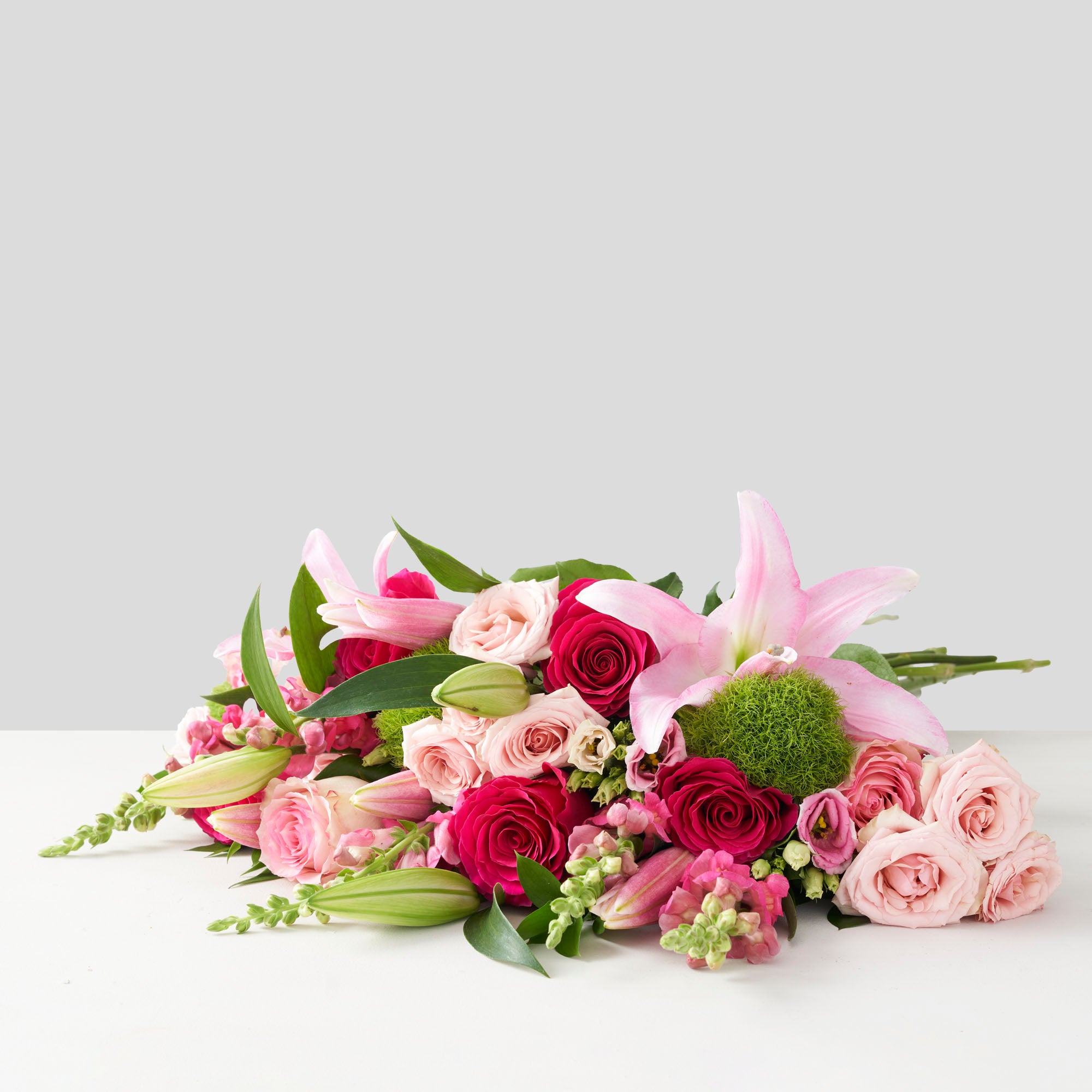 Bouquet of pink flowers, including roses, lilies, snapdragon, and lisianthus.