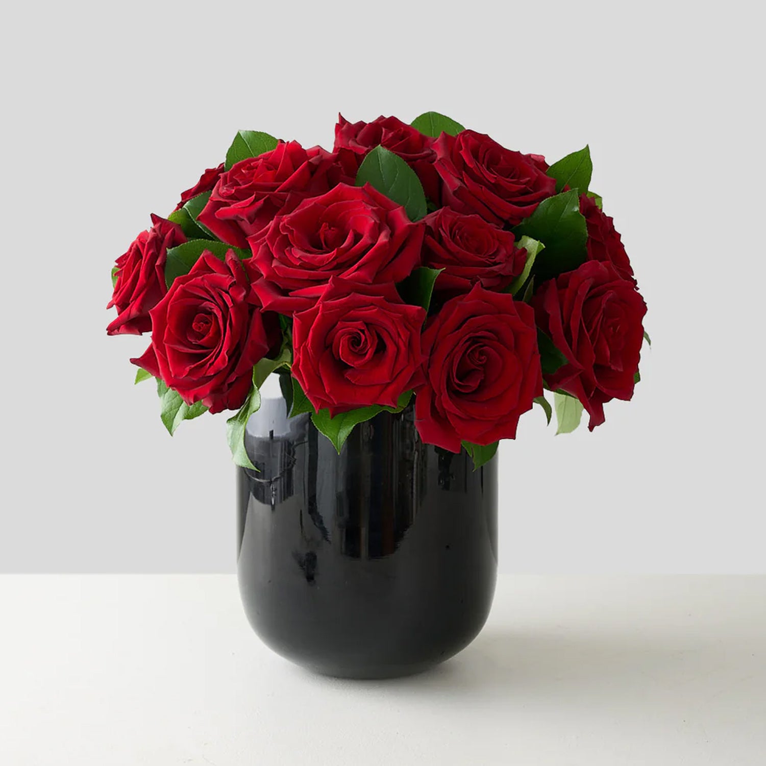 arrangement of red roses in a black glass vase.