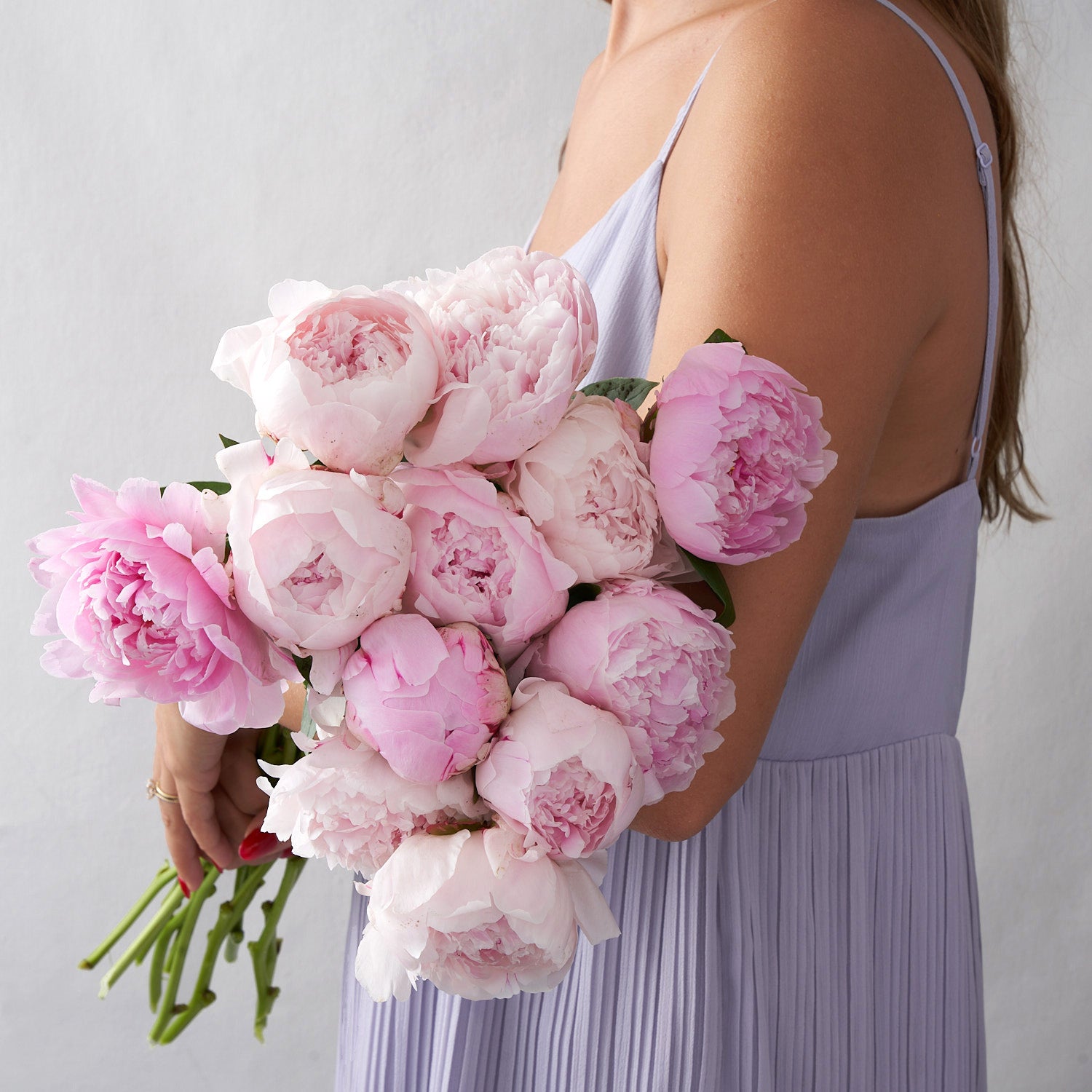 Woman in purple holding bouquet of peonies