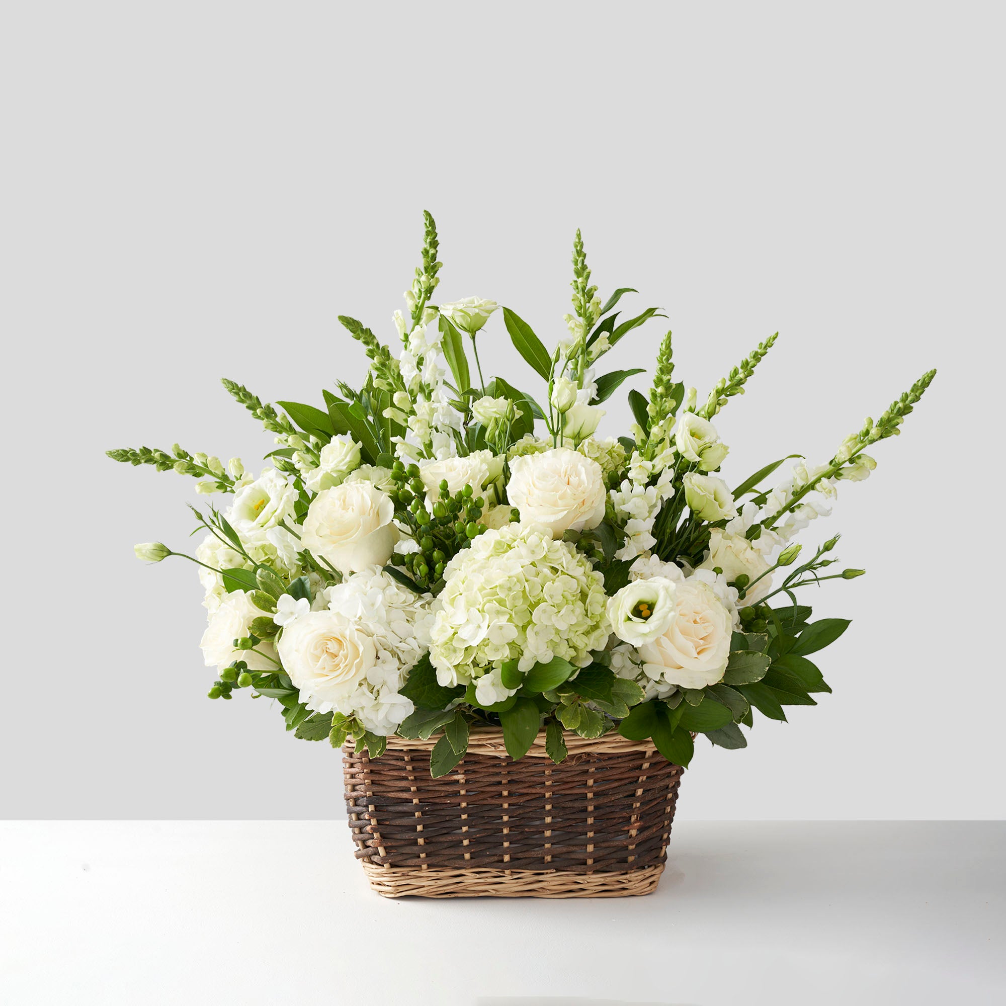 Large spray of all white flowers in natural basket.