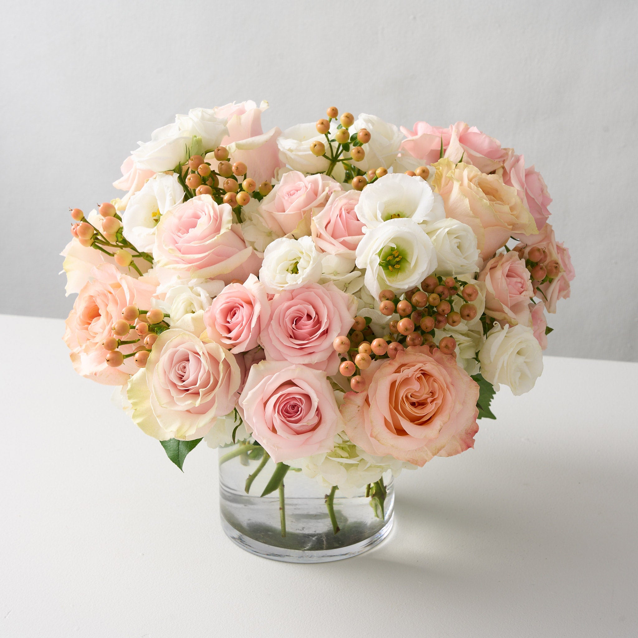 sophie pink roses, peach hypericum, white hydrangea in a clear cylinder vase