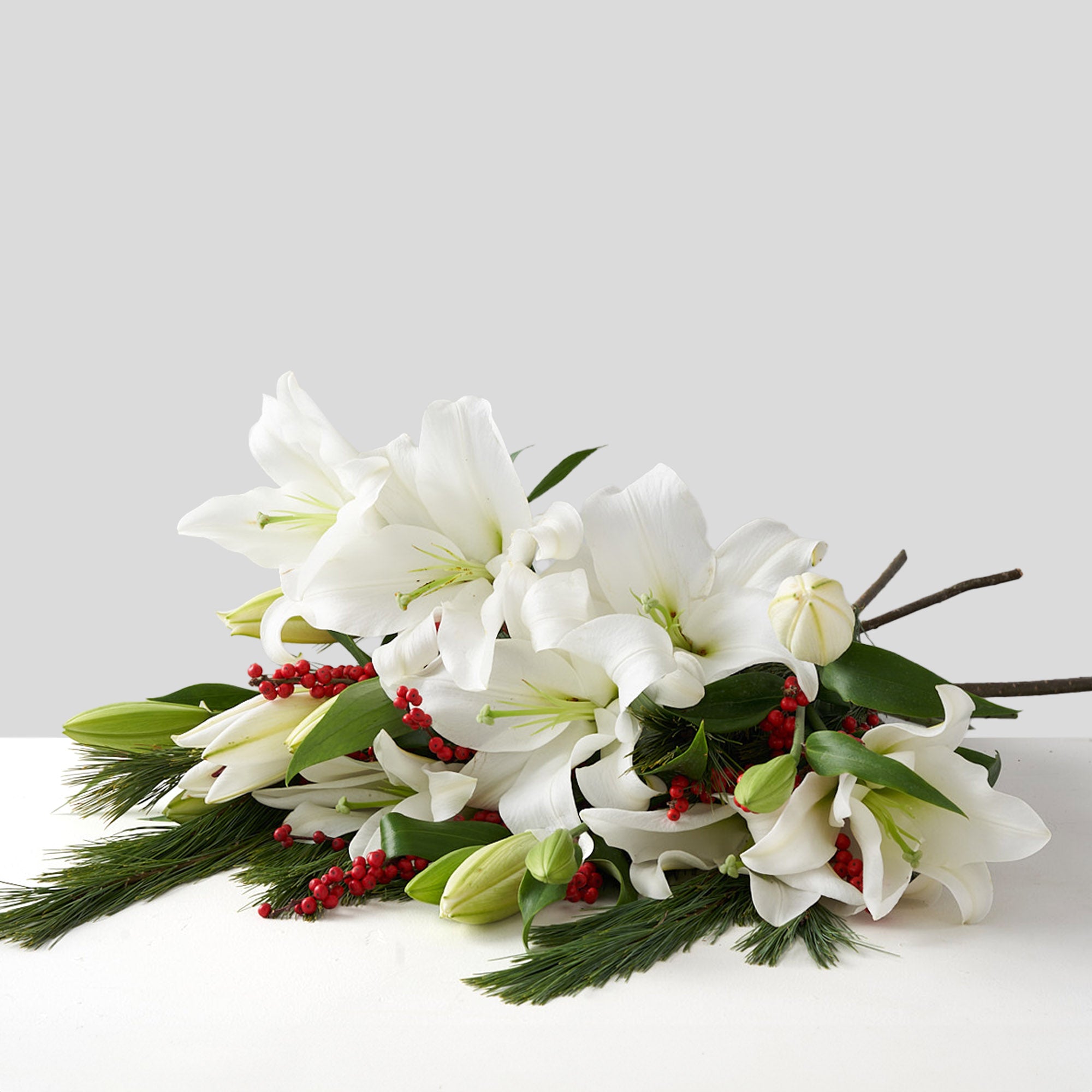 Bouquet of white lilies, red berries, and pine.